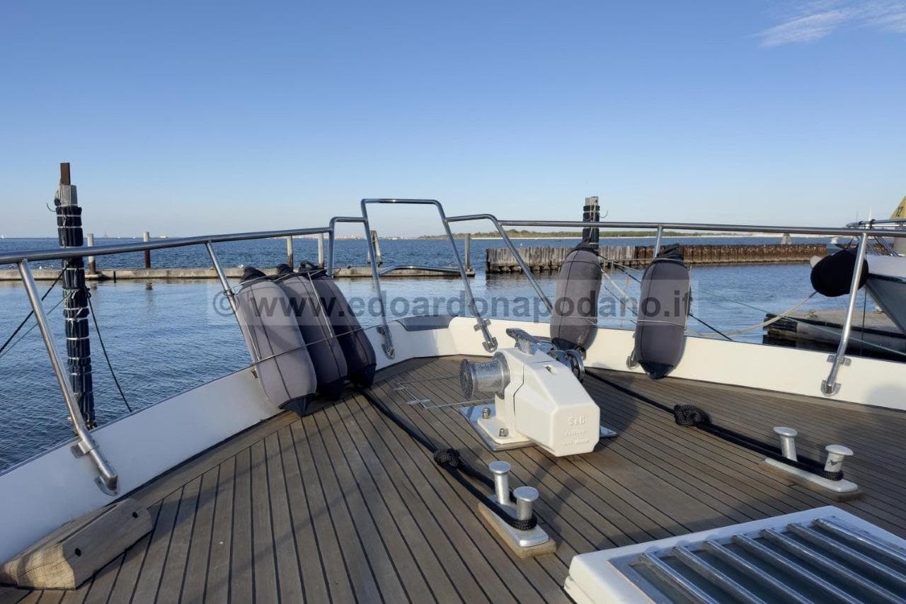 Deck view of 1973 Cantieri di Pisa Atlas yacht, featuring mooring equipment and ocean backdrop.
