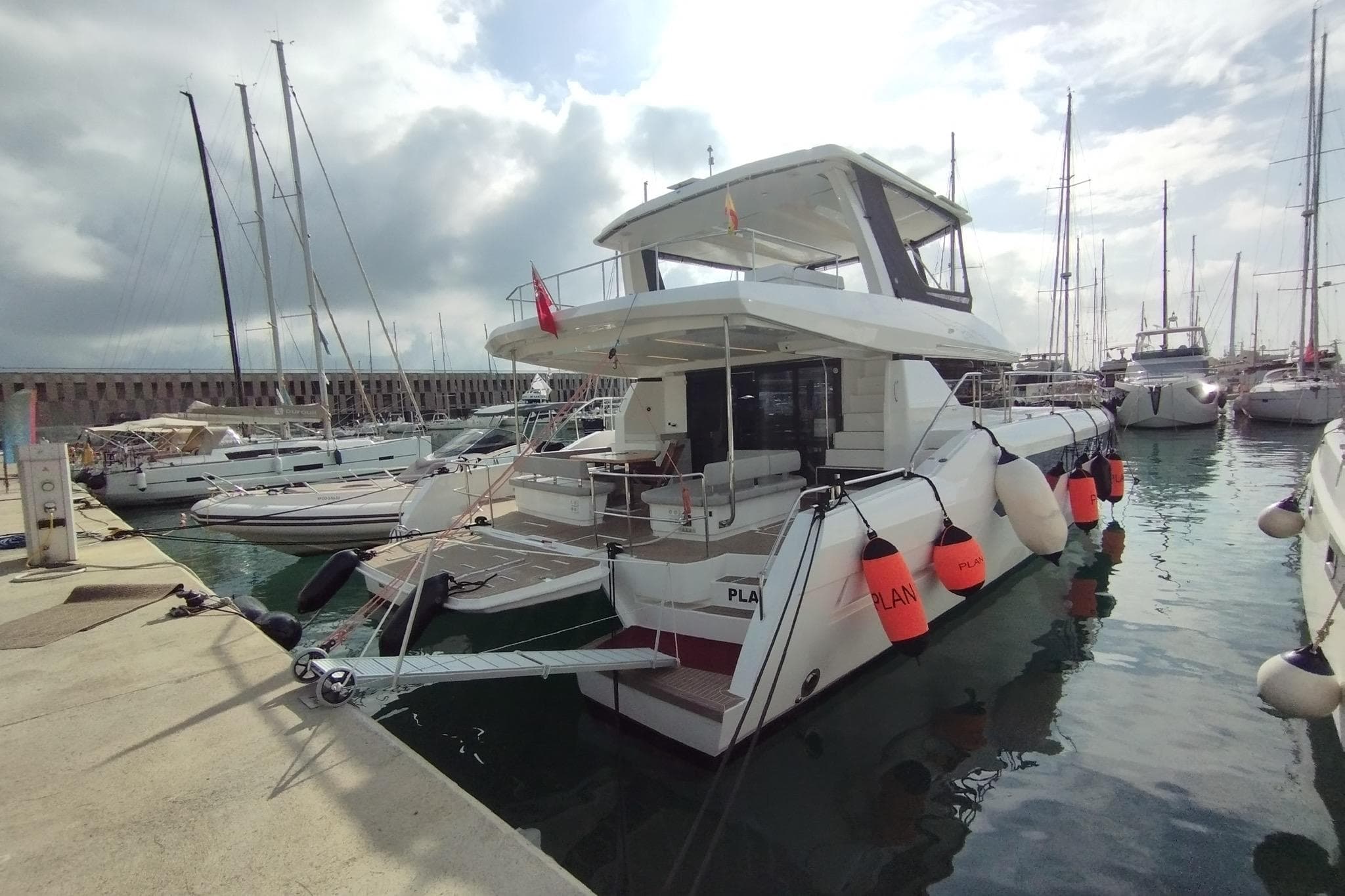2024 Leopard 53 Powercat docked at marina, surrounded by other boats under cloudy sky.