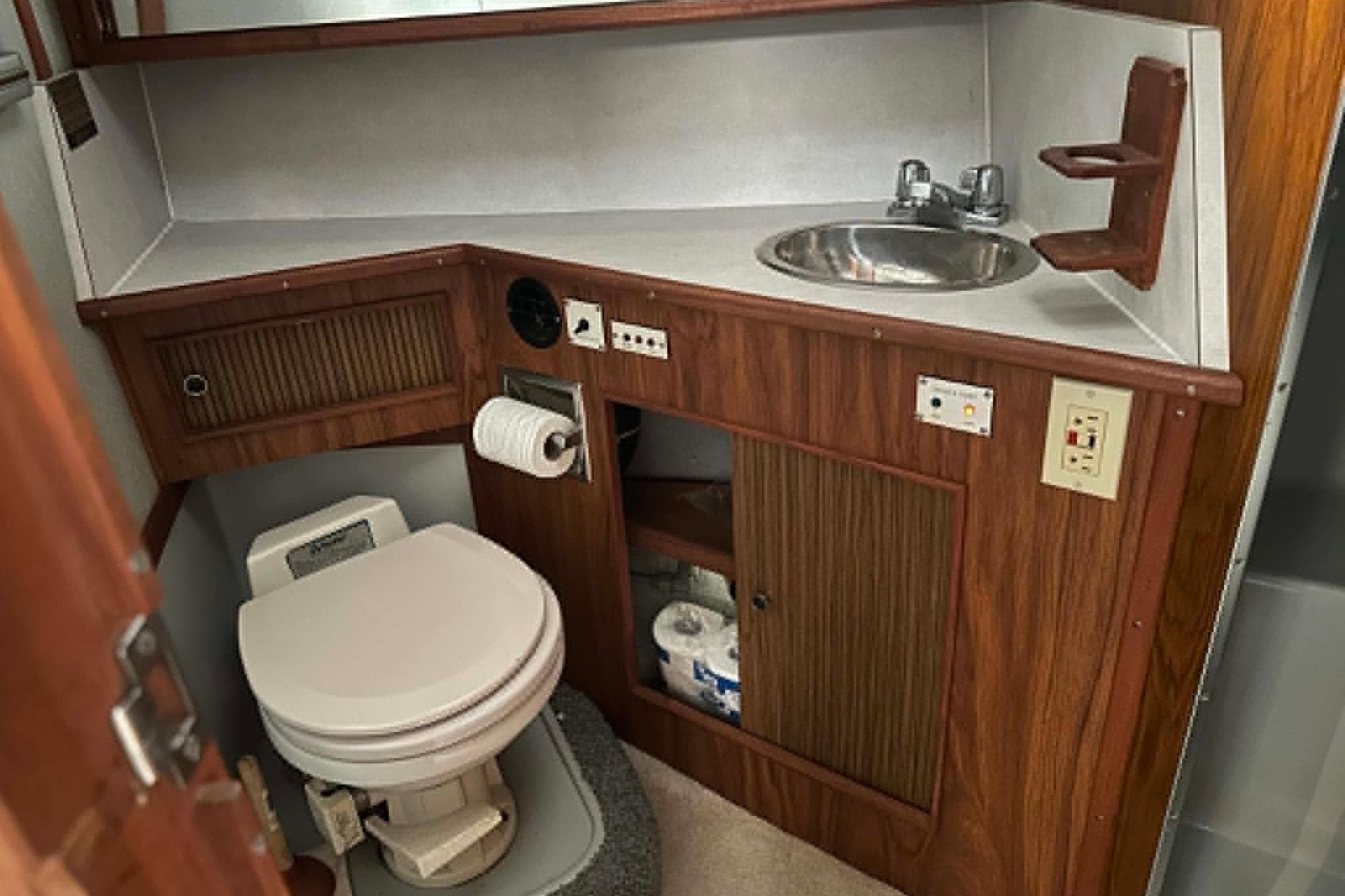 1988 Sea Ray 390 Express Cruiser bathroom with wood cabinetry, sink, and toilet.