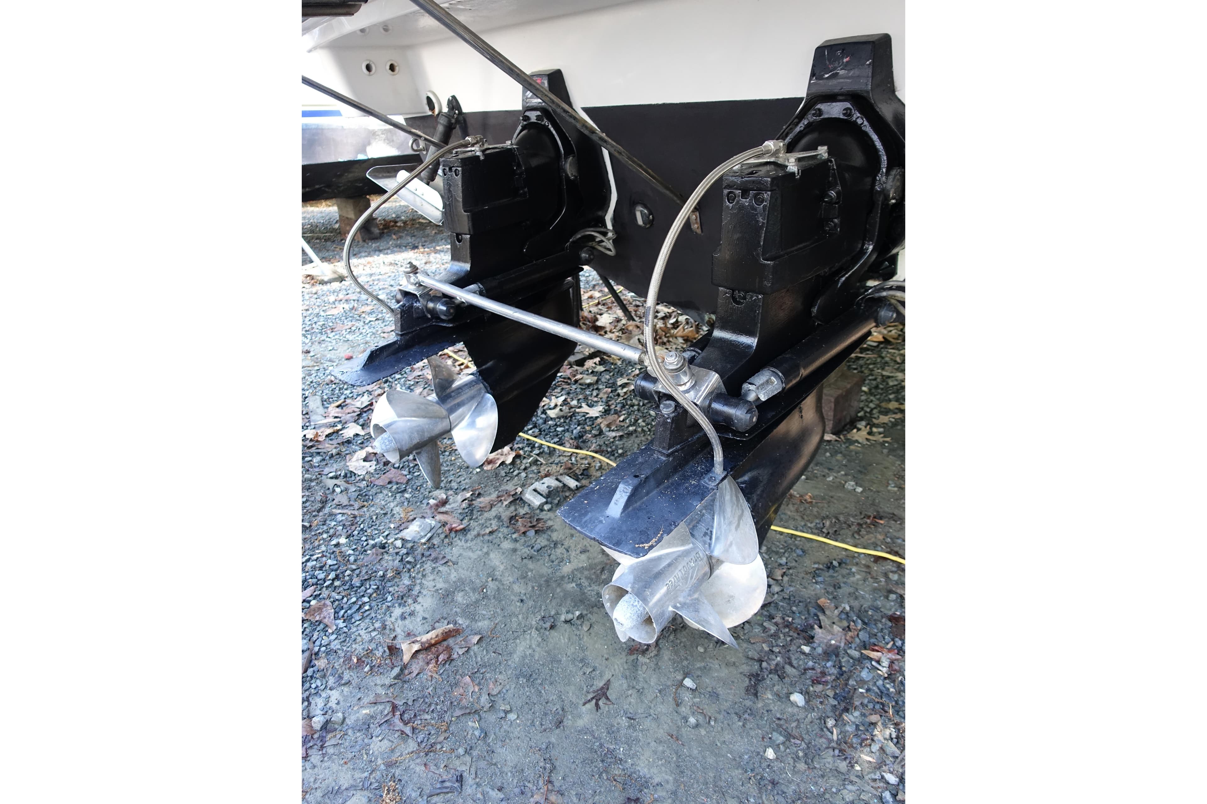 2002 Formula 330 Sun Sport boat propellers and outdrives on gravel surface.
