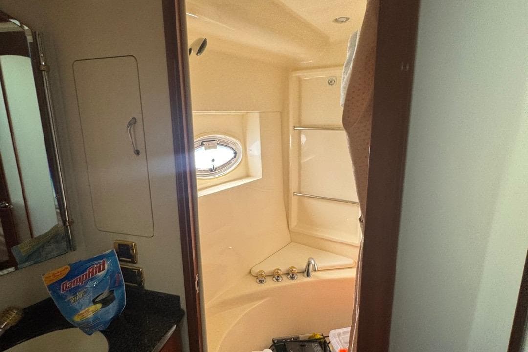 Bathroom interior of 2004 Carver 564 Cockpit Motor Yacht with shower and porthole window.