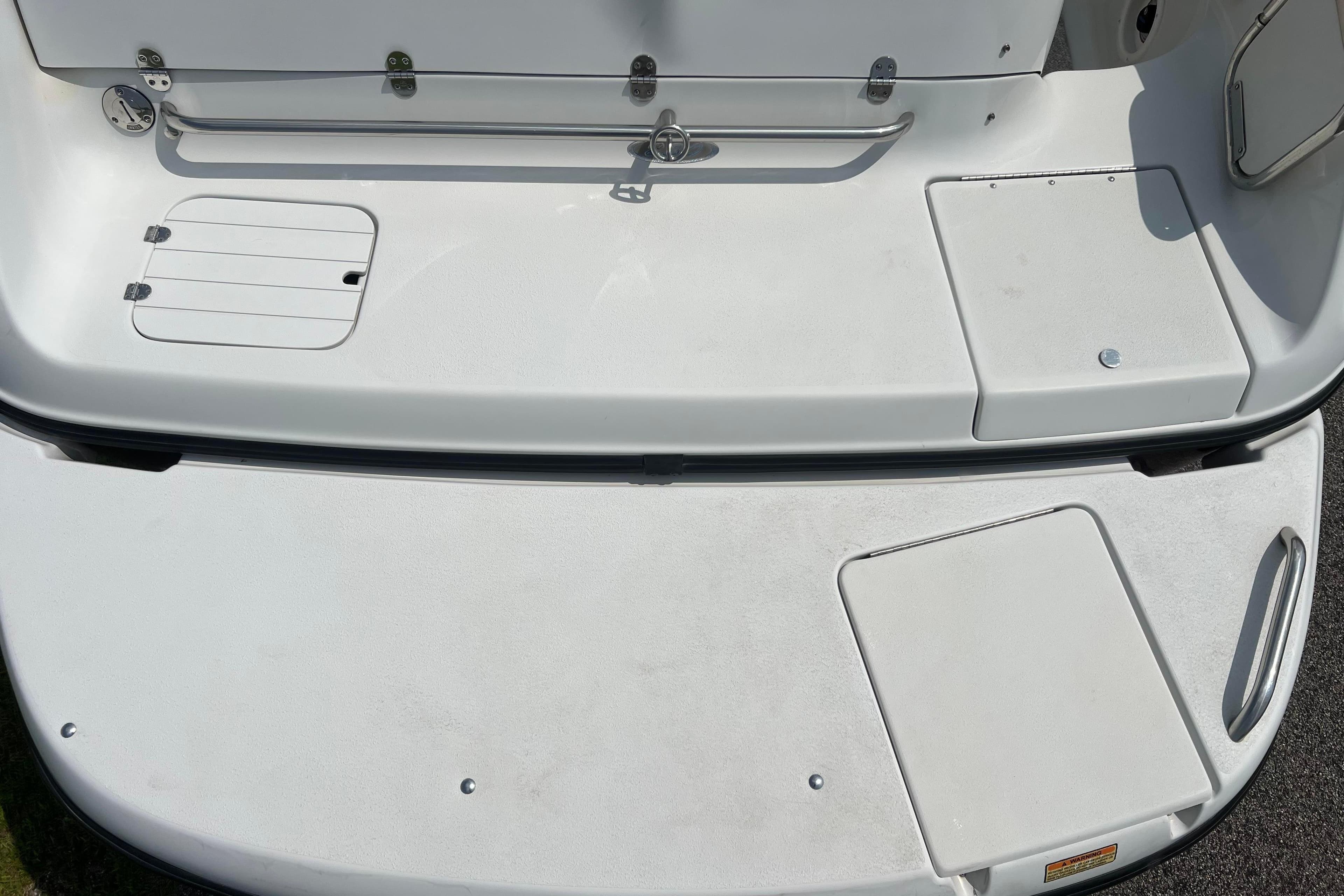 2003 Crownline 230 BR boat deck with storage compartments and clean white surface.