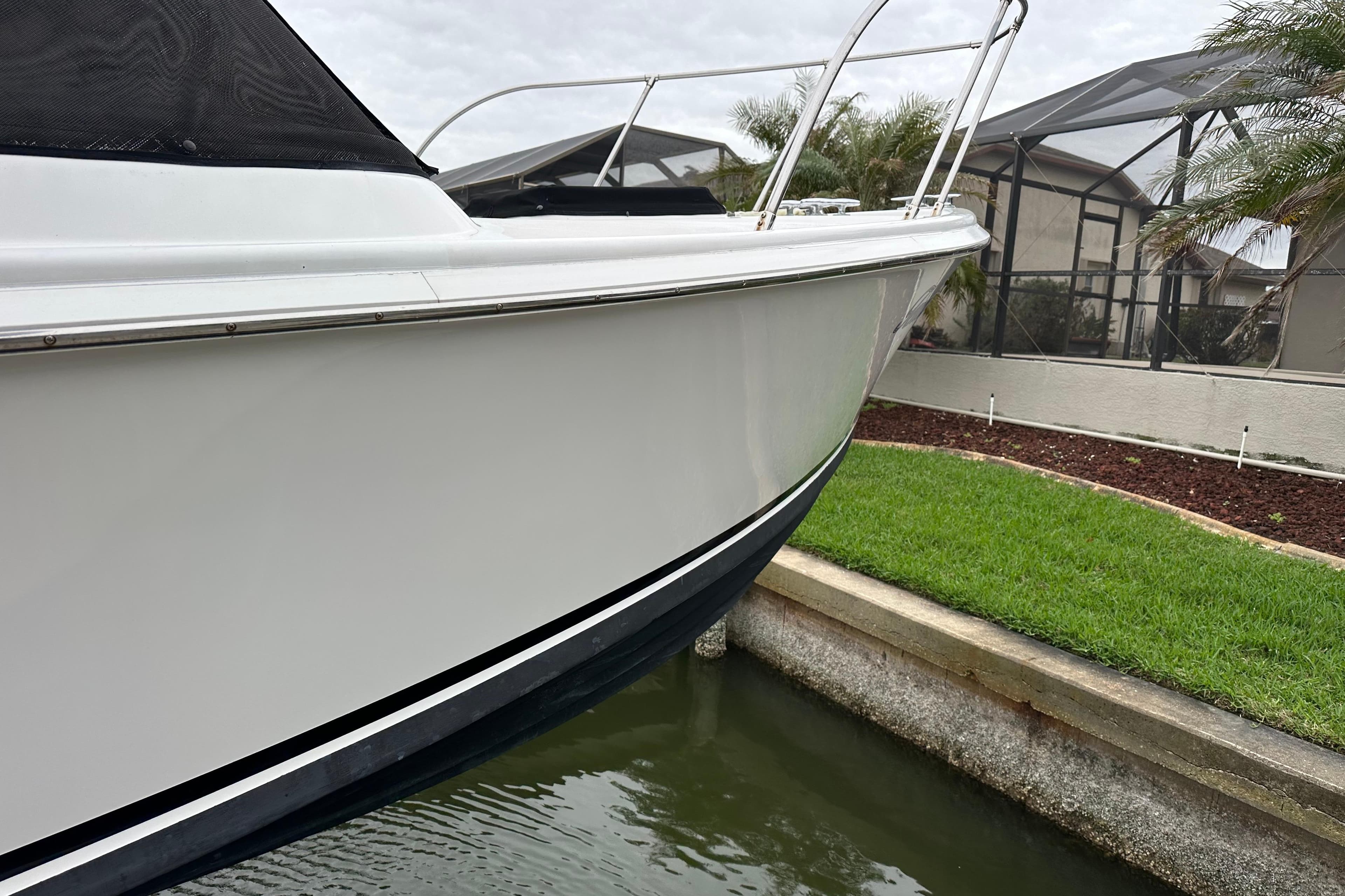 1975 Bertram 31 boat docked near a grassy area, showcasing sleek white hull.