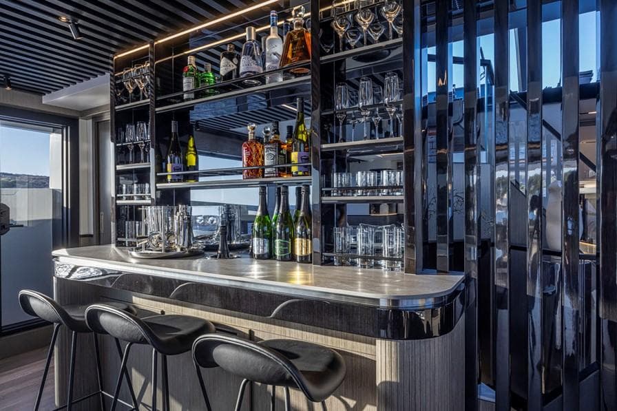 Luxurious yacht bar interior with sleek design, featuring stocked shelves and modern seating. Pearl 82, 2026.