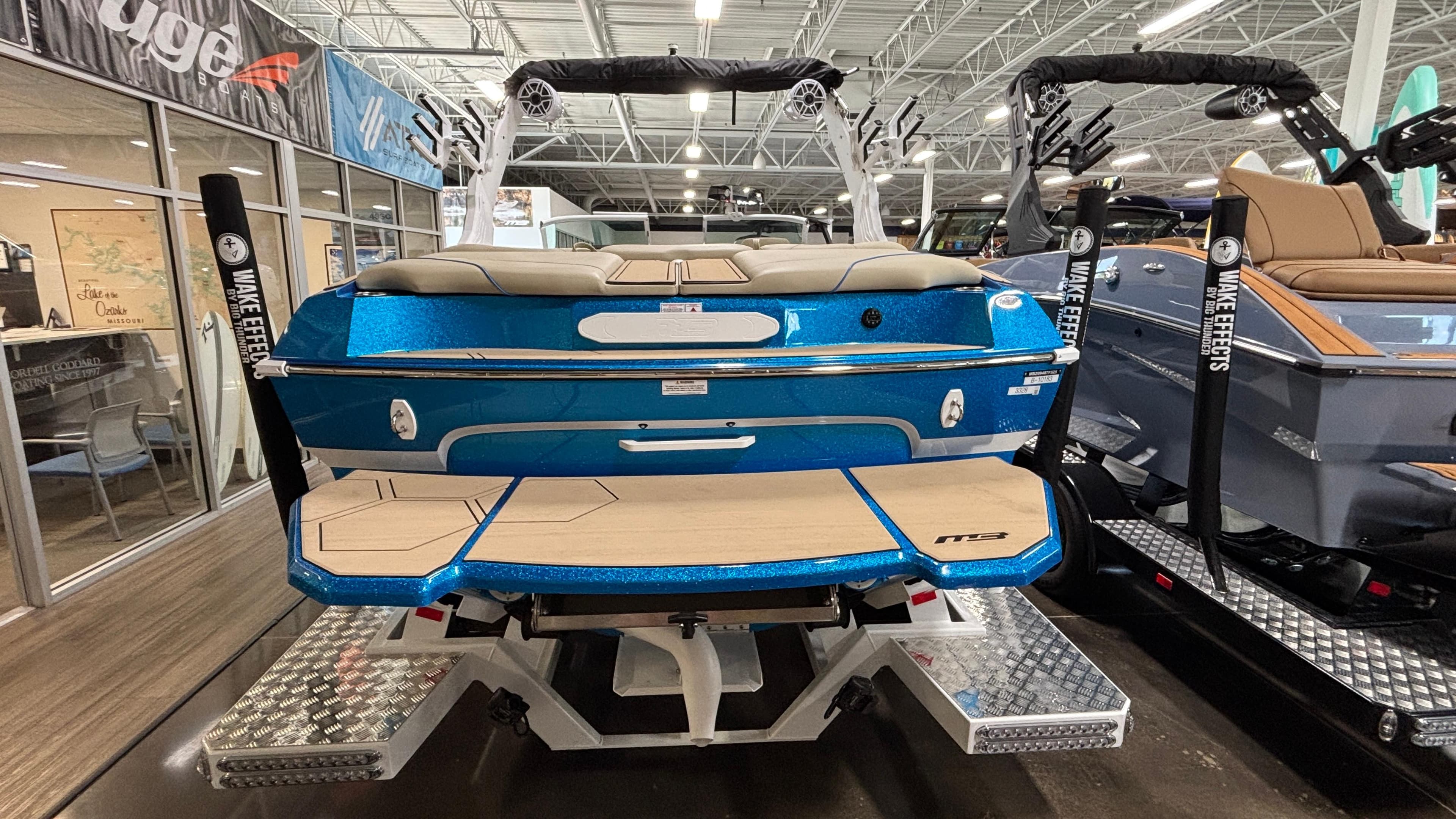 2025 MB B52 23 Classic boat in showroom, blue exterior, wakeboard racks, luxury seating.
