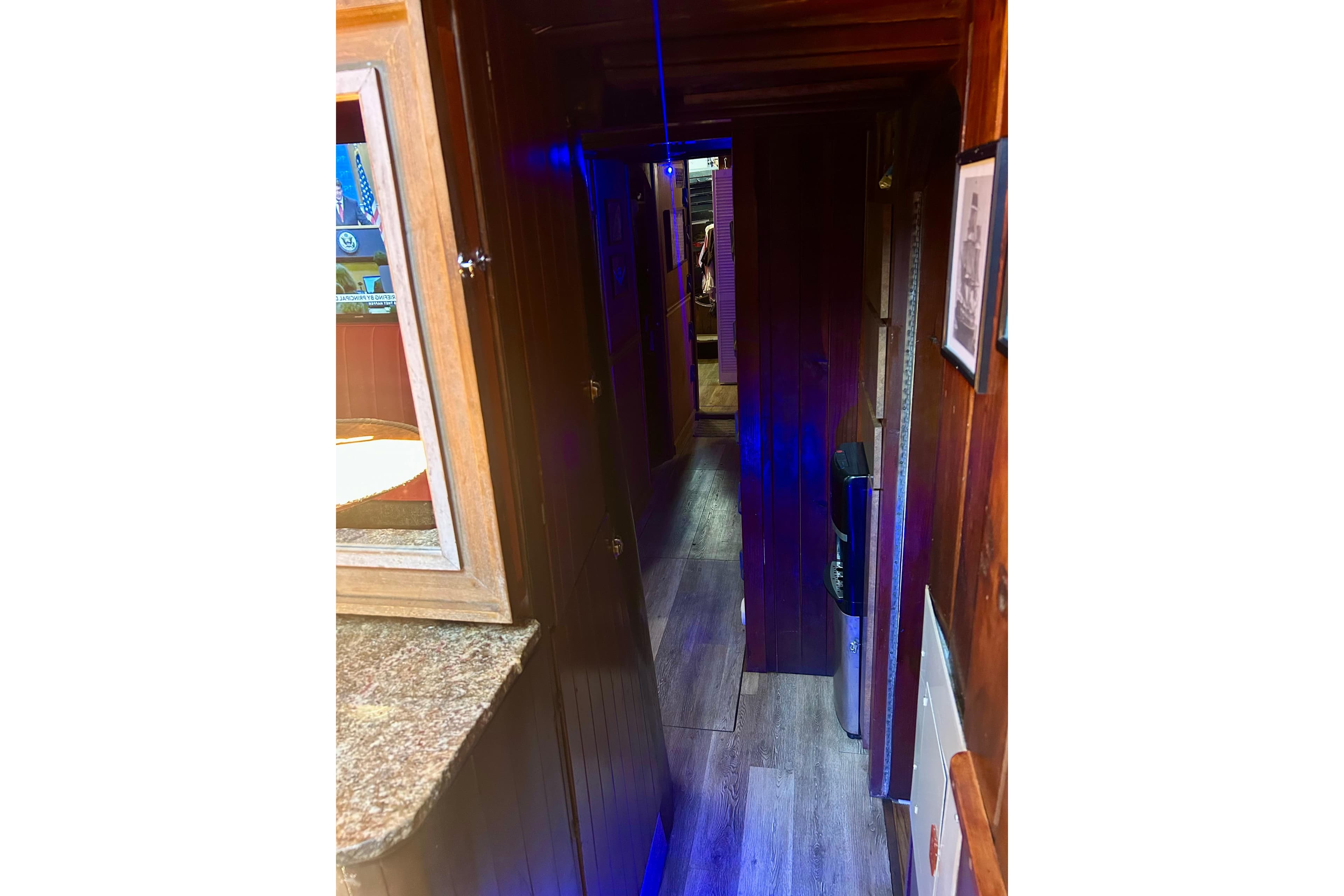 Narrow wooden hallway inside a 1977 Custom Brigantine boat with blue lighting.