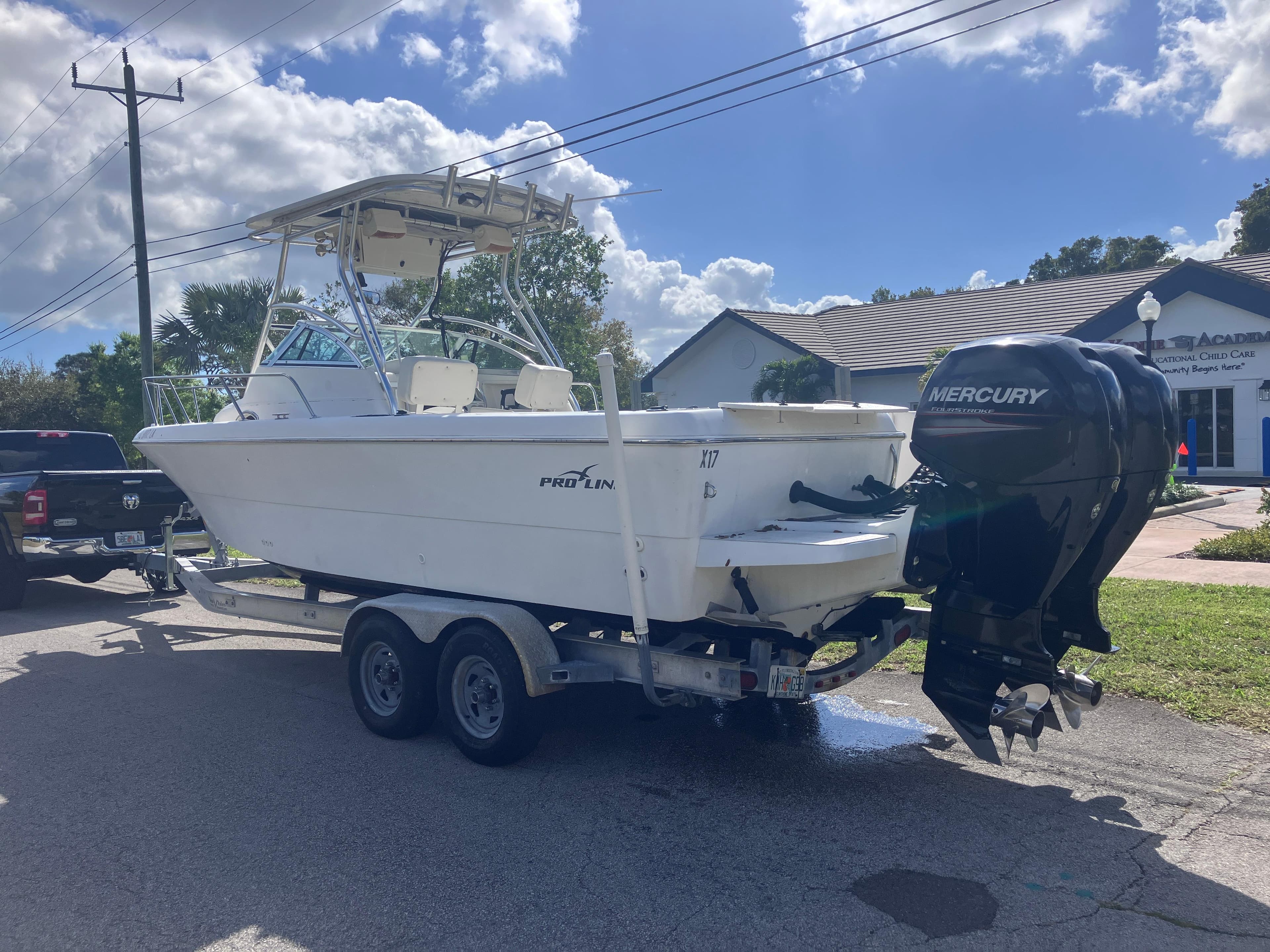 1998 Pro-Line 241 Walkaround boat on trailer with Mercury outboard motor, parked outdoors.