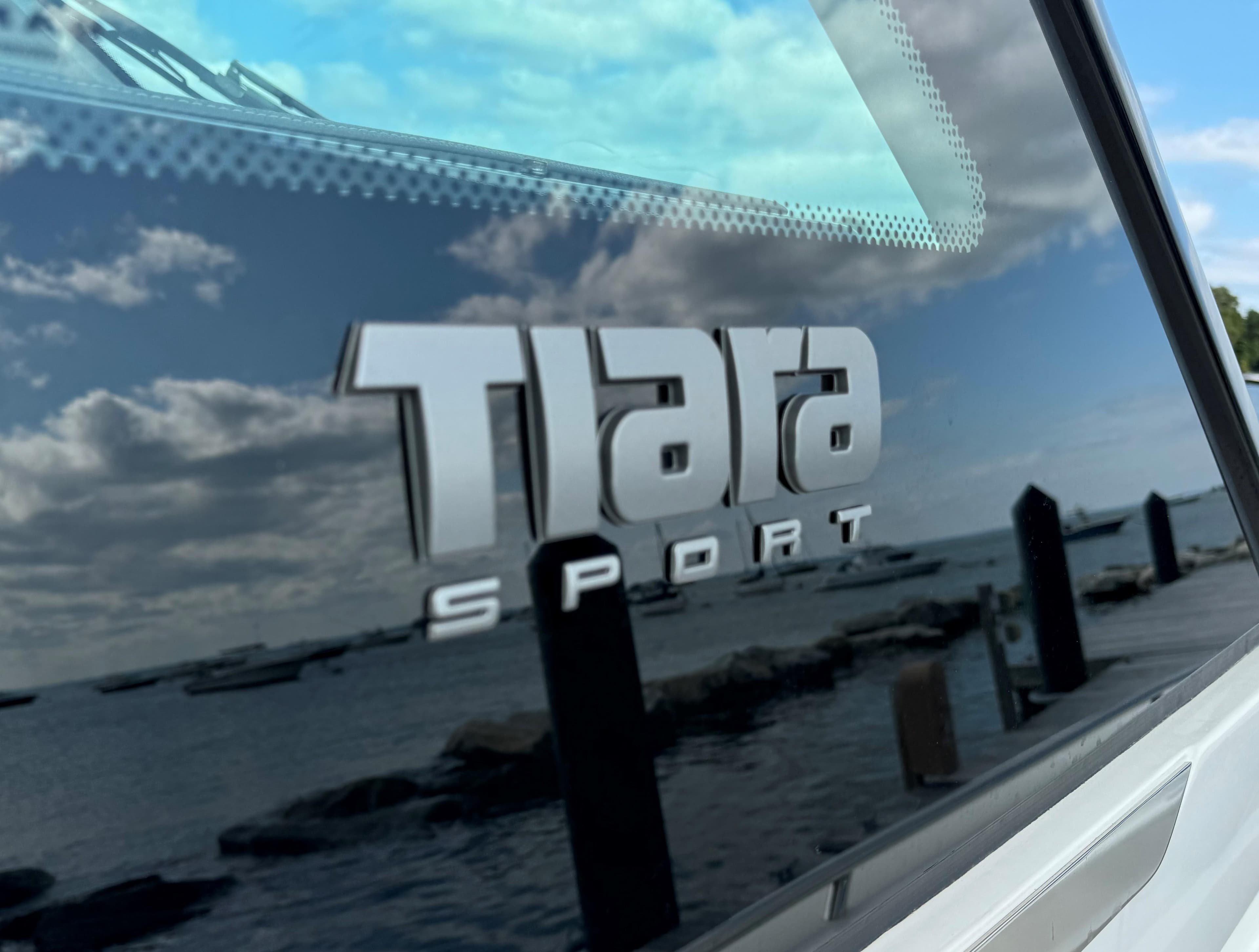 Tiara Sport 34 LS 2020 logo on boat window with scenic waterfront reflection.
