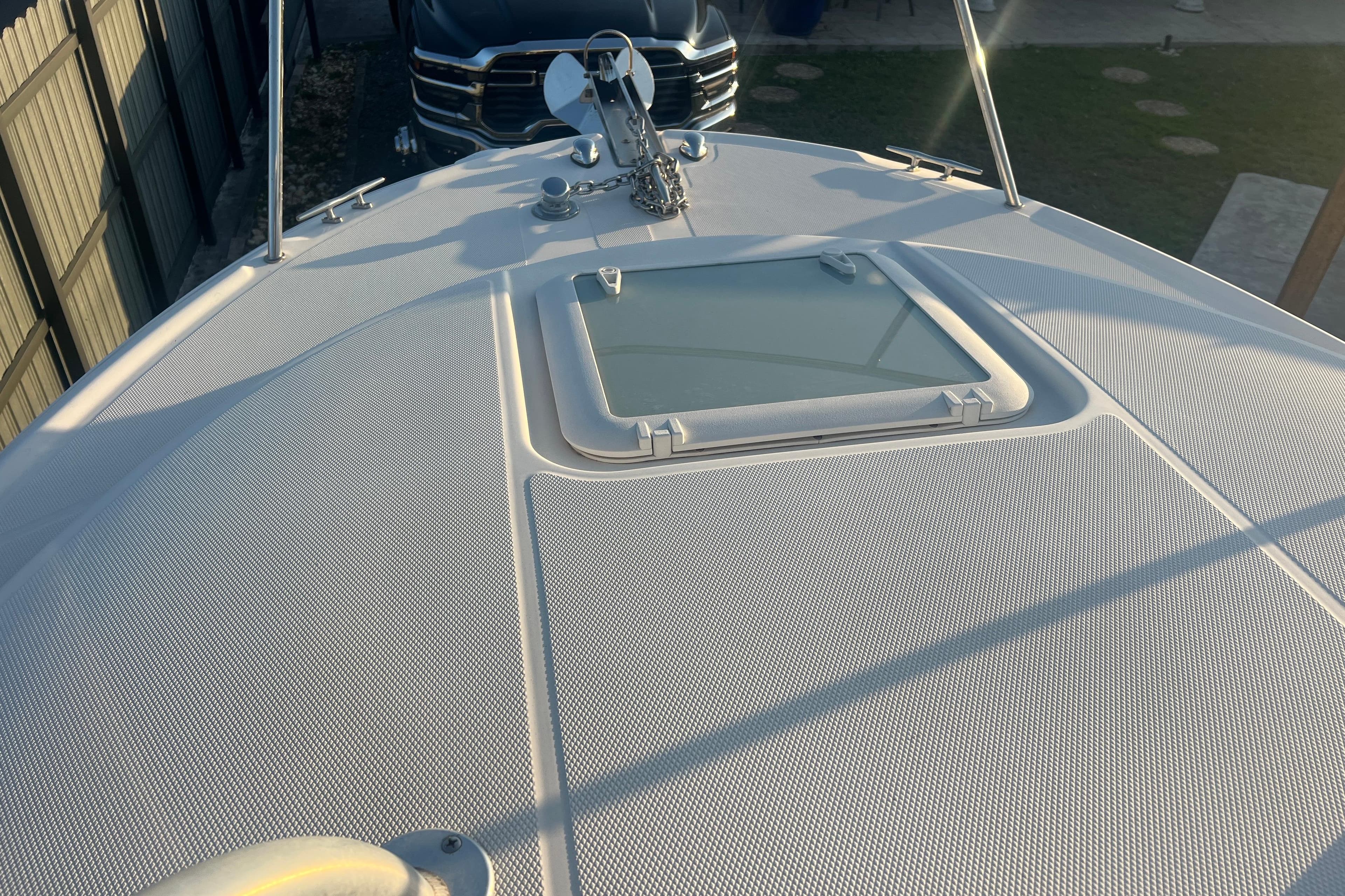 2011 Wellcraft 232 Coastal boat deck with hatch, parked near a vehicle.