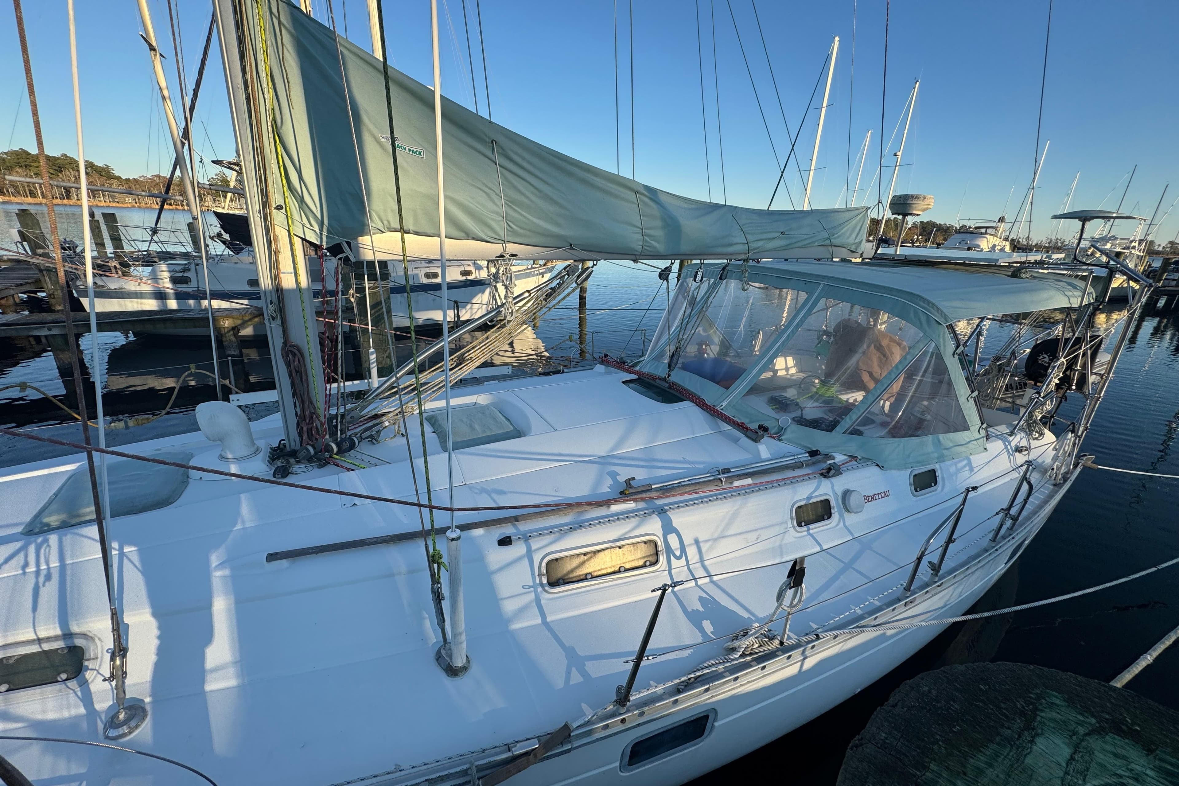 1994 Beneteau 40 sailboat docked at marina, featuring green canopy and clear skies.