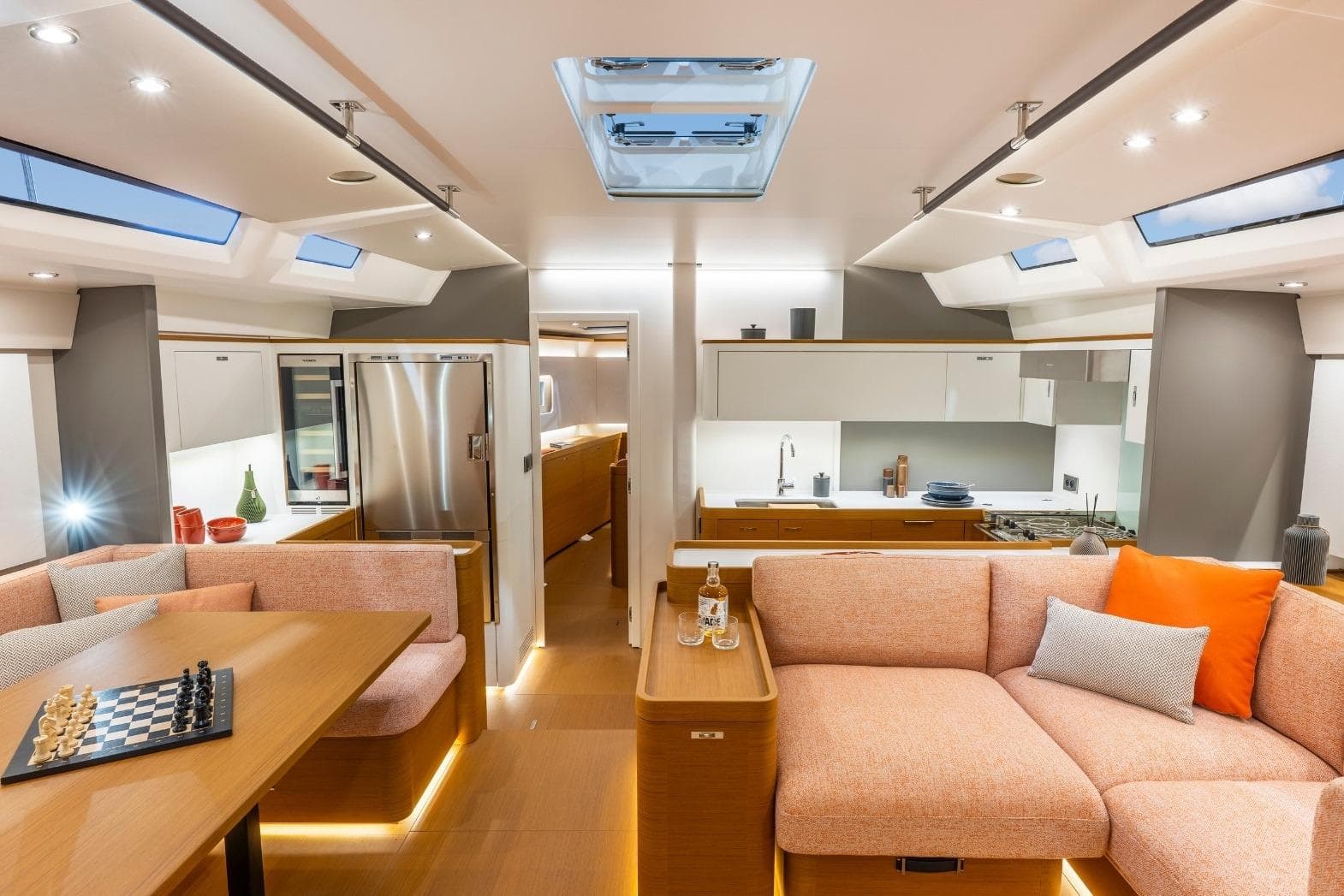 Luxurious interior of 2026 Beneteau First 60 yacht with modern kitchen and cozy seating area.
