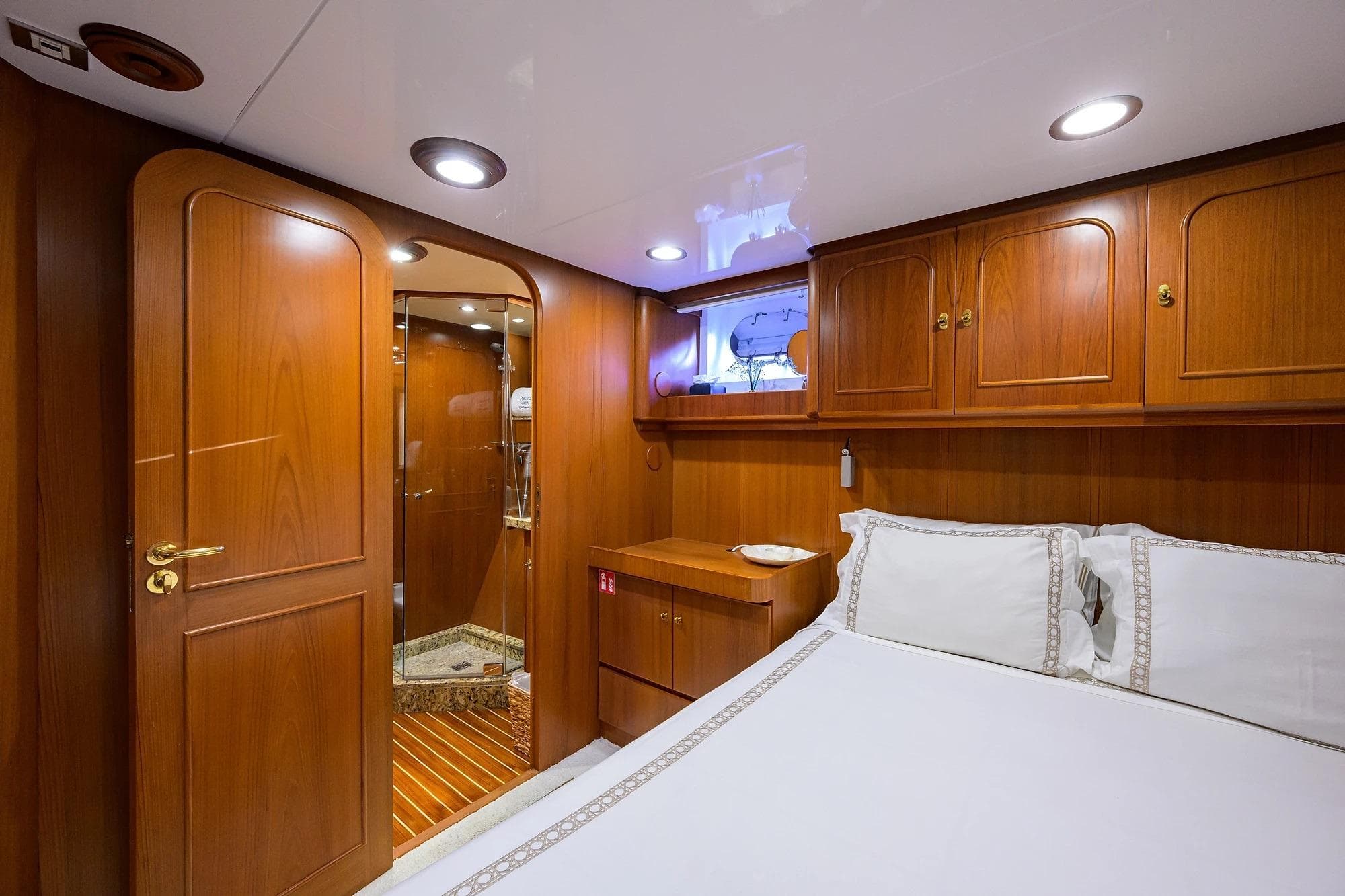 Luxurious wooden cabin interior on 1986 Jongert 85 yacht, featuring elegant bedding and cabinetry.