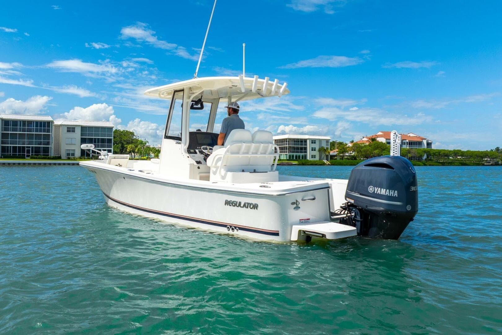 2021 Regulator 26XO boat on water with Yamaha engine, clear sky, and waterfront buildings.