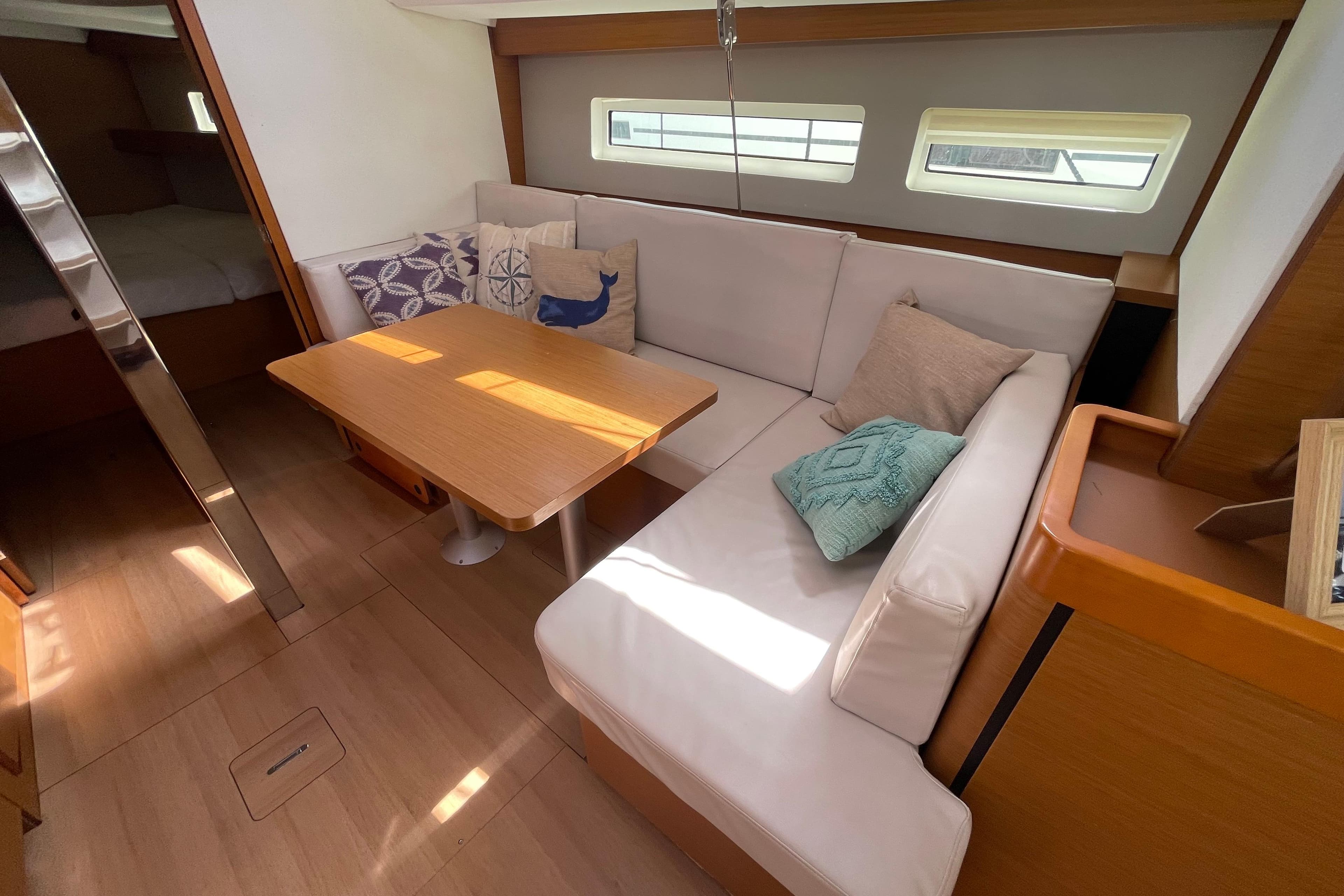 Interior of 2018 Jeanneau Sun Odyssey 440 yacht with cozy seating and wooden table.