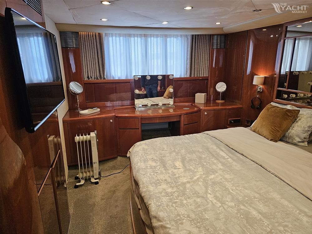 Luxurious bedroom interior of 2009 Princess 21M yacht with elegant wood finish and cozy bedding.