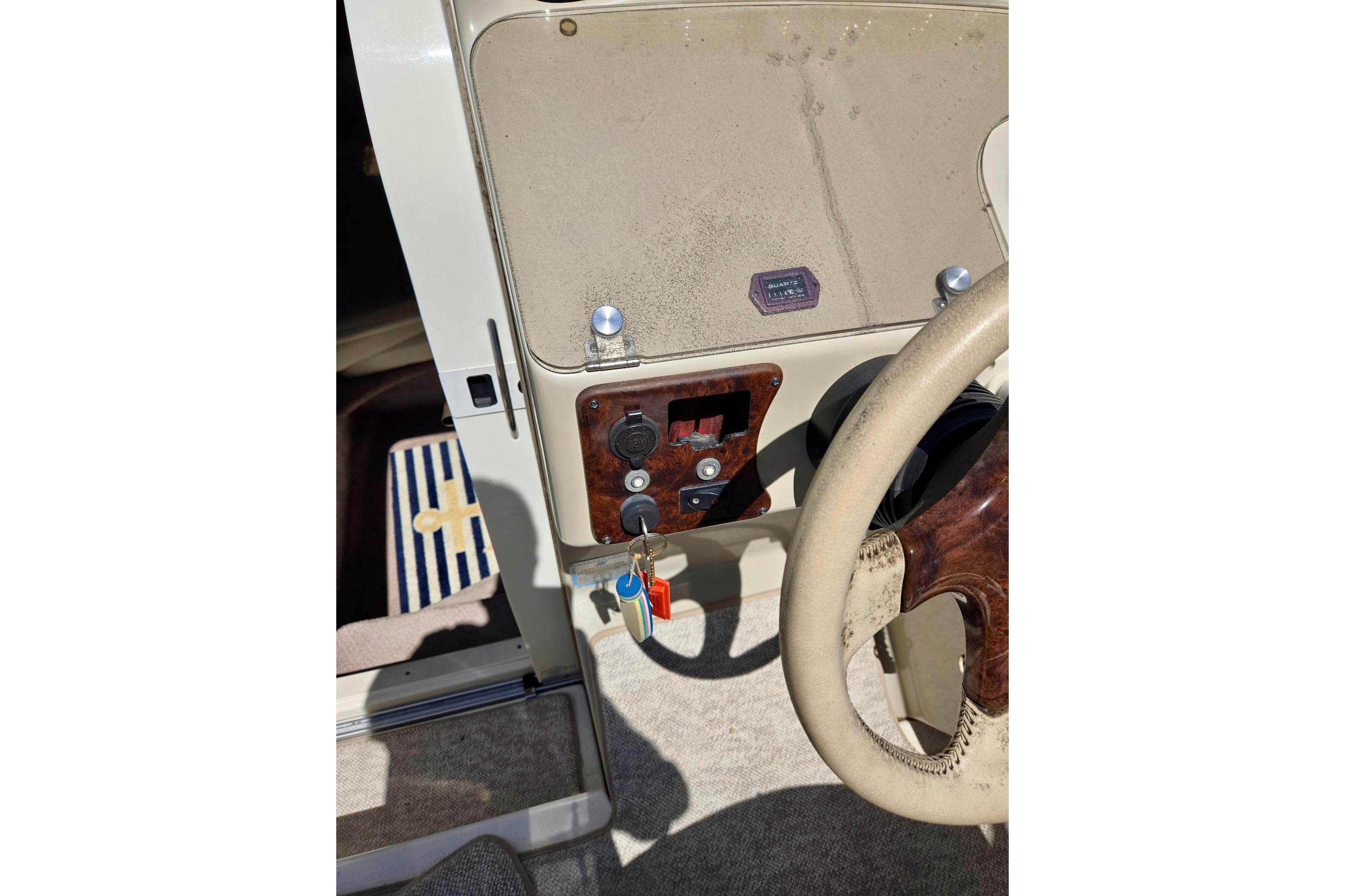 1999 Rinker Fiesta Vee 270 boat dashboard with steering wheel and ignition keys.