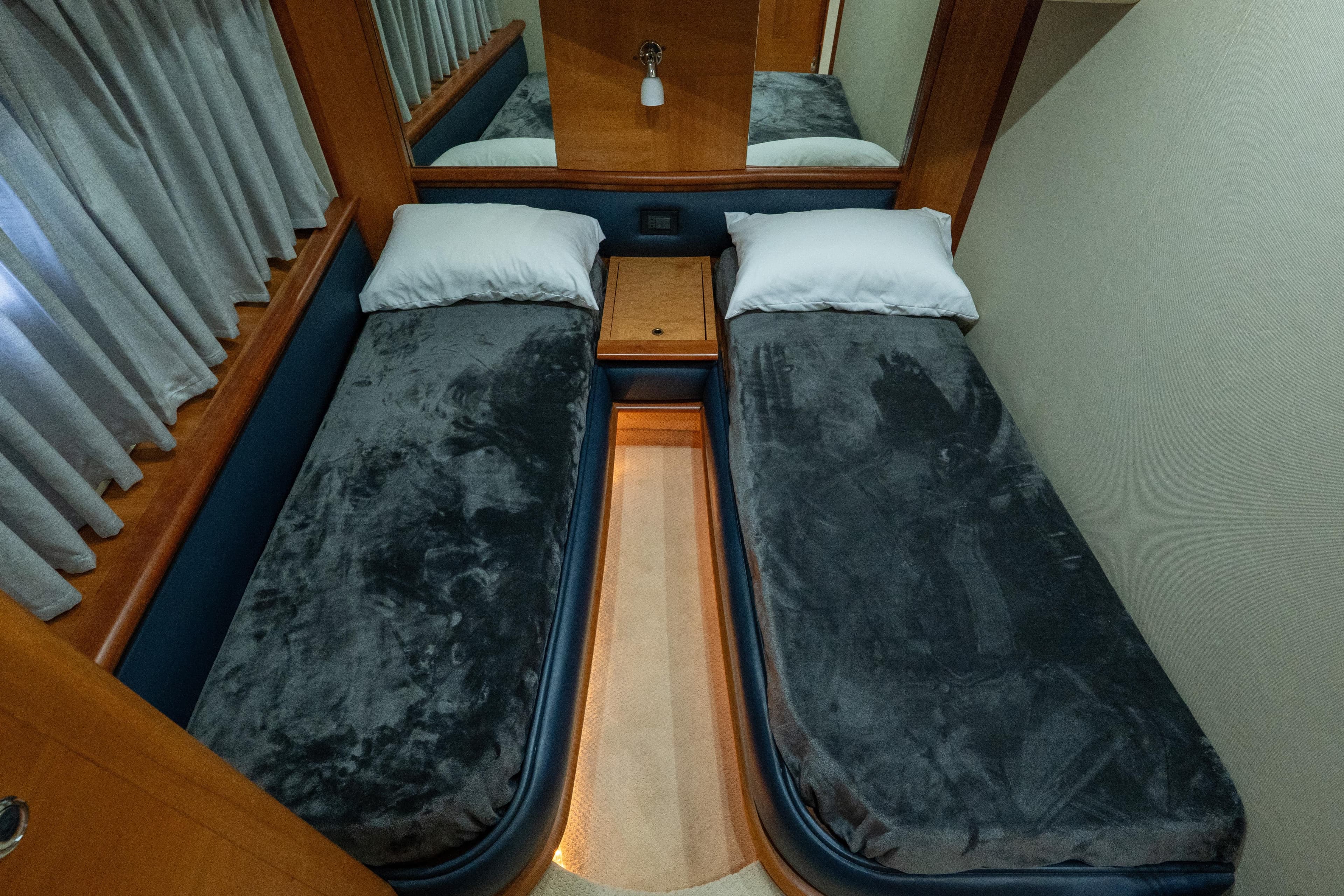 Twin beds in a 2008 Azimut 62E yacht cabin with plush gray bedding.