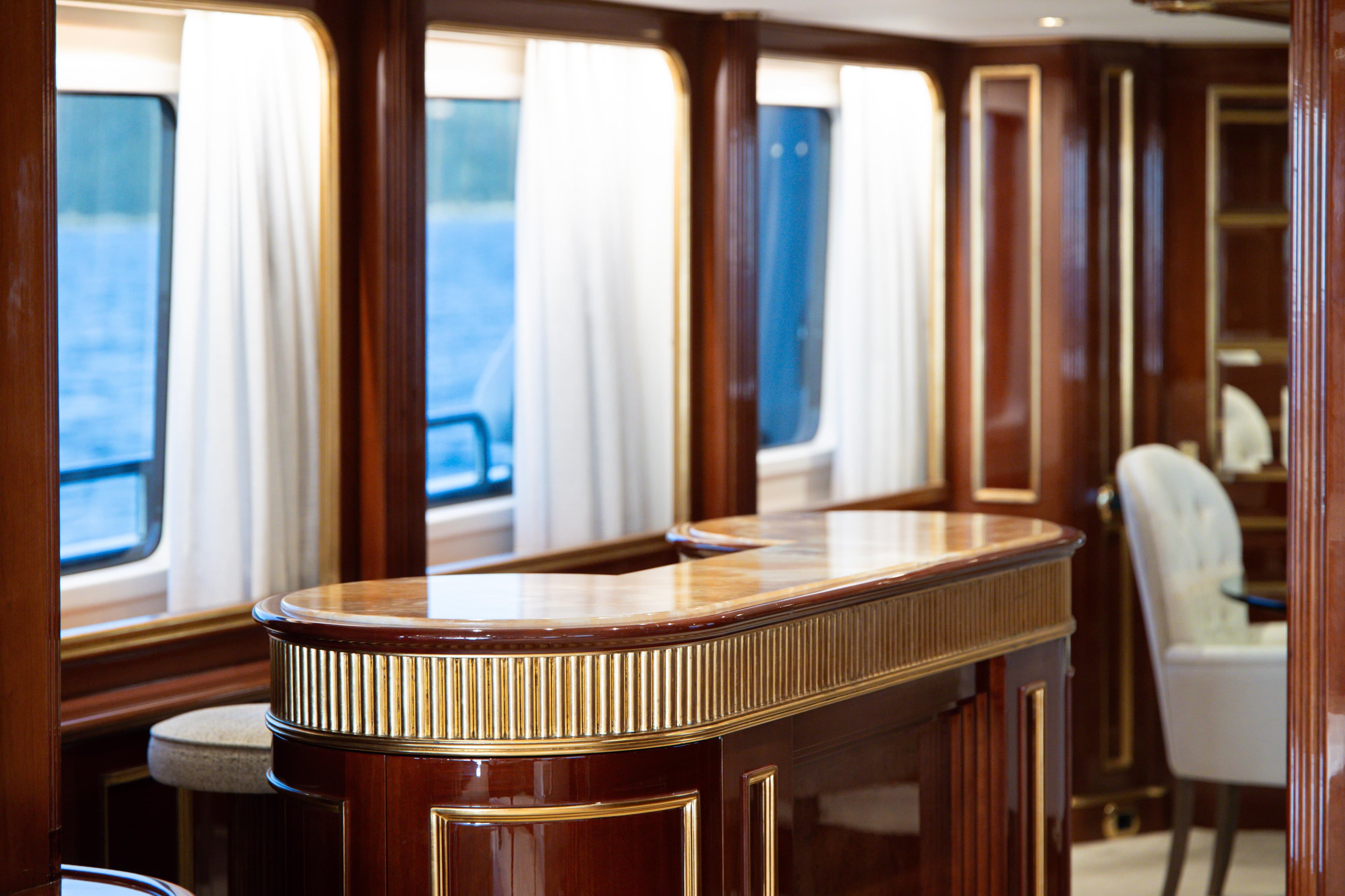 Luxurious interior of 2000 Benetti Classic 115 yacht with elegant wood finishes and large windows.