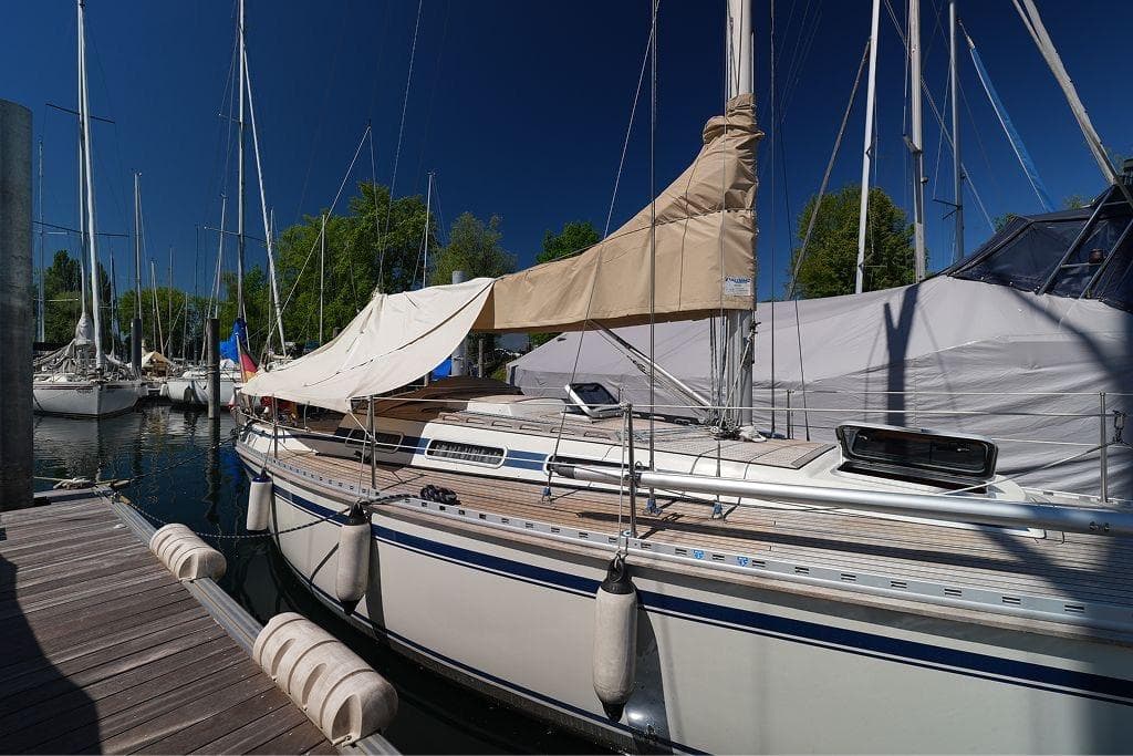 Sailboat docked at marina, Faurby 1992 model, sunny day, clear blue sky.