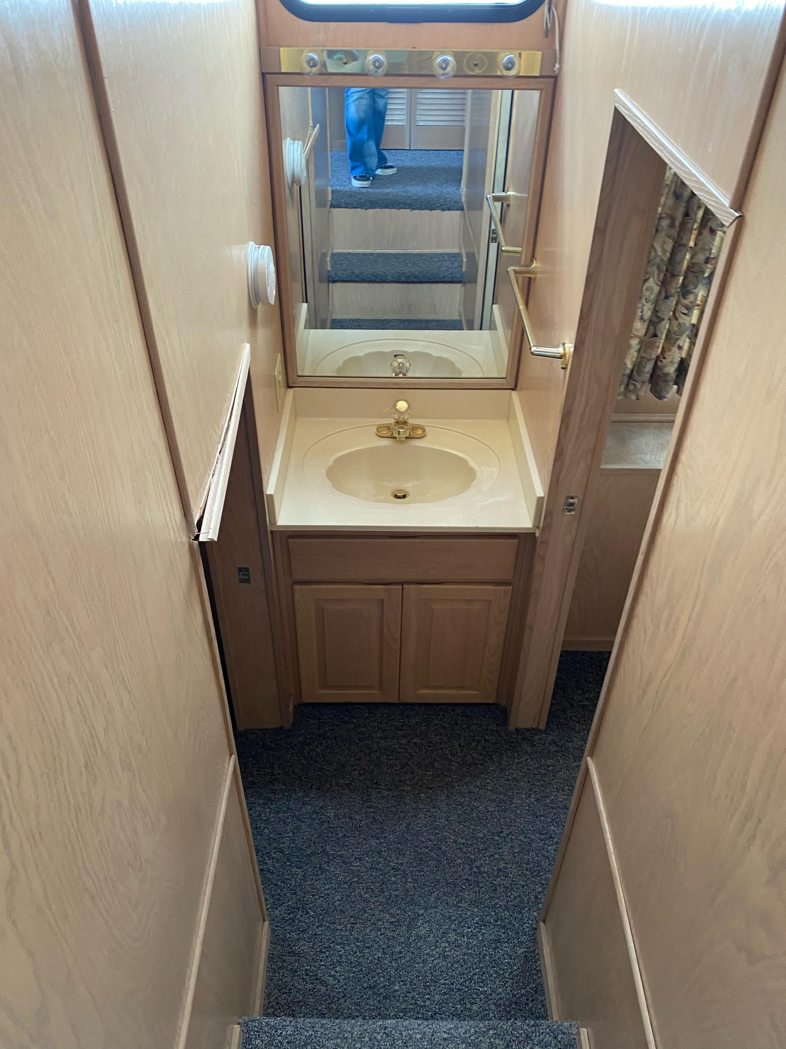 2001 Stardust Cruisers bathroom with wooden cabinetry, mirror, and sink.