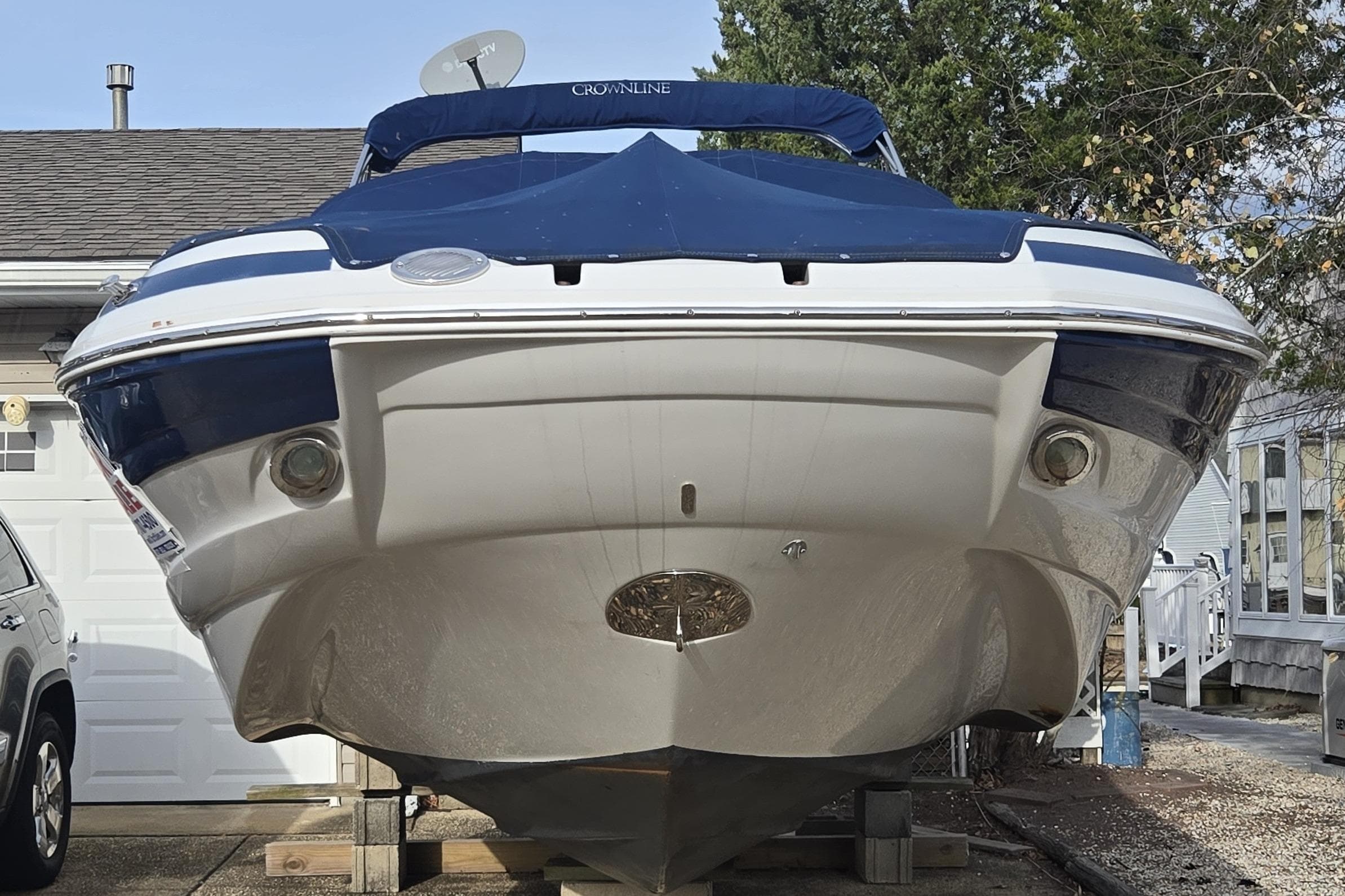 2012 Crownline Eclipse E4 boat on blocks, parked near a house and car.