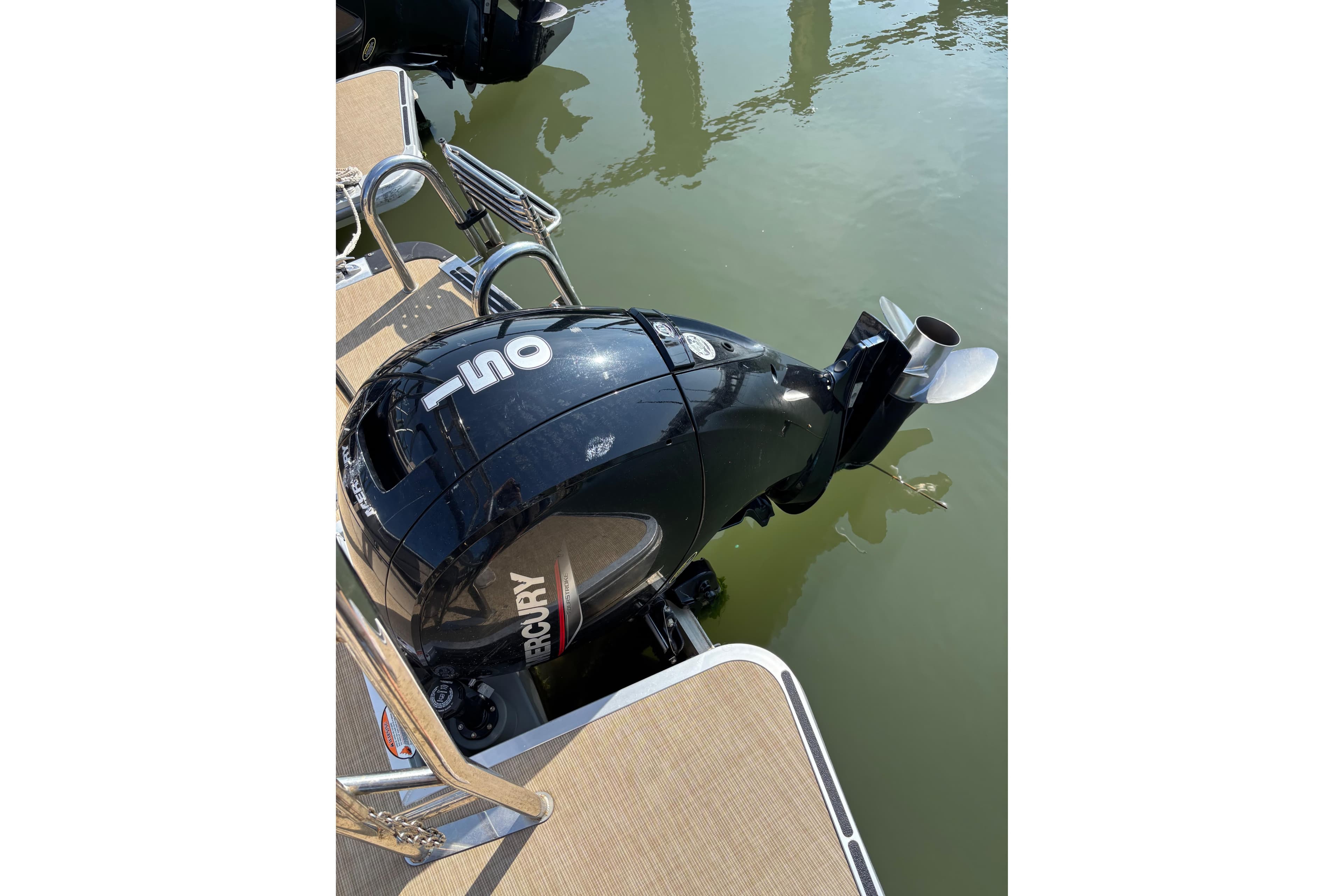 Outboard motor on 2024 Harris HCX23 boat, docked on calm water.