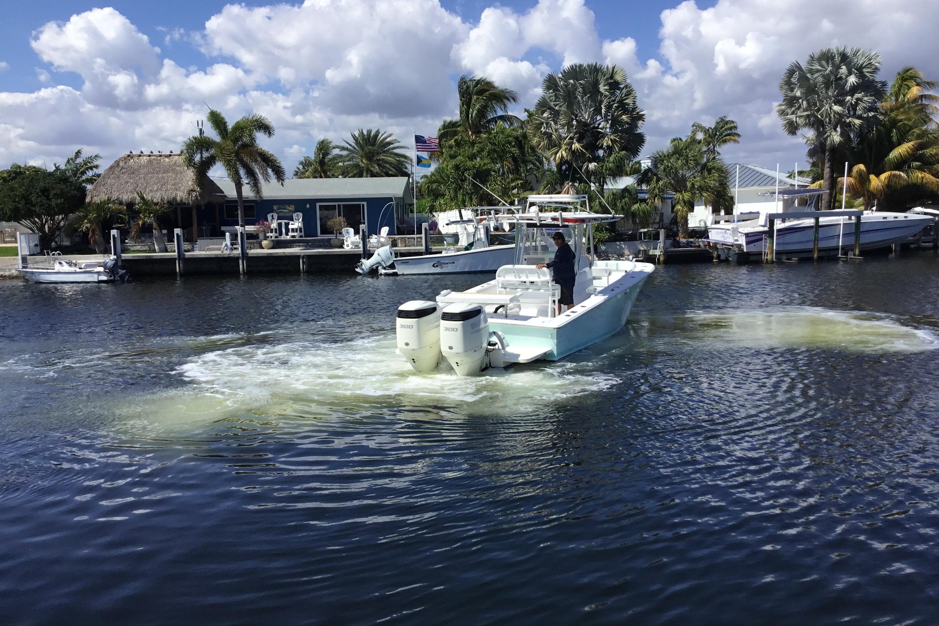2000 Jupiter 31 Center Console boat navigating a scenic waterfront with palm trees.