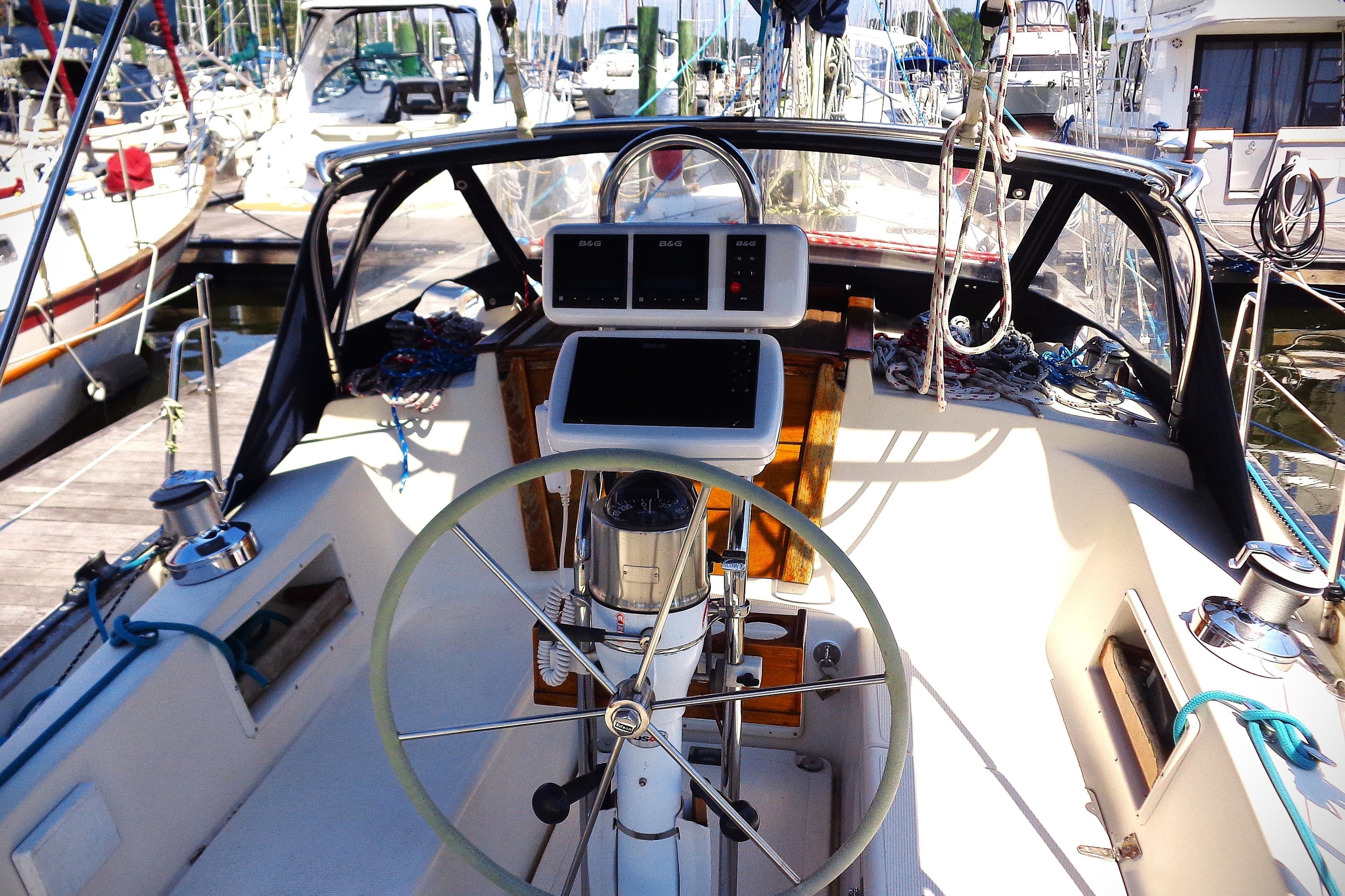 Cockpit of a 1995 Pacific Seacraft 37 sailboat, featuring steering wheel and navigation instruments.