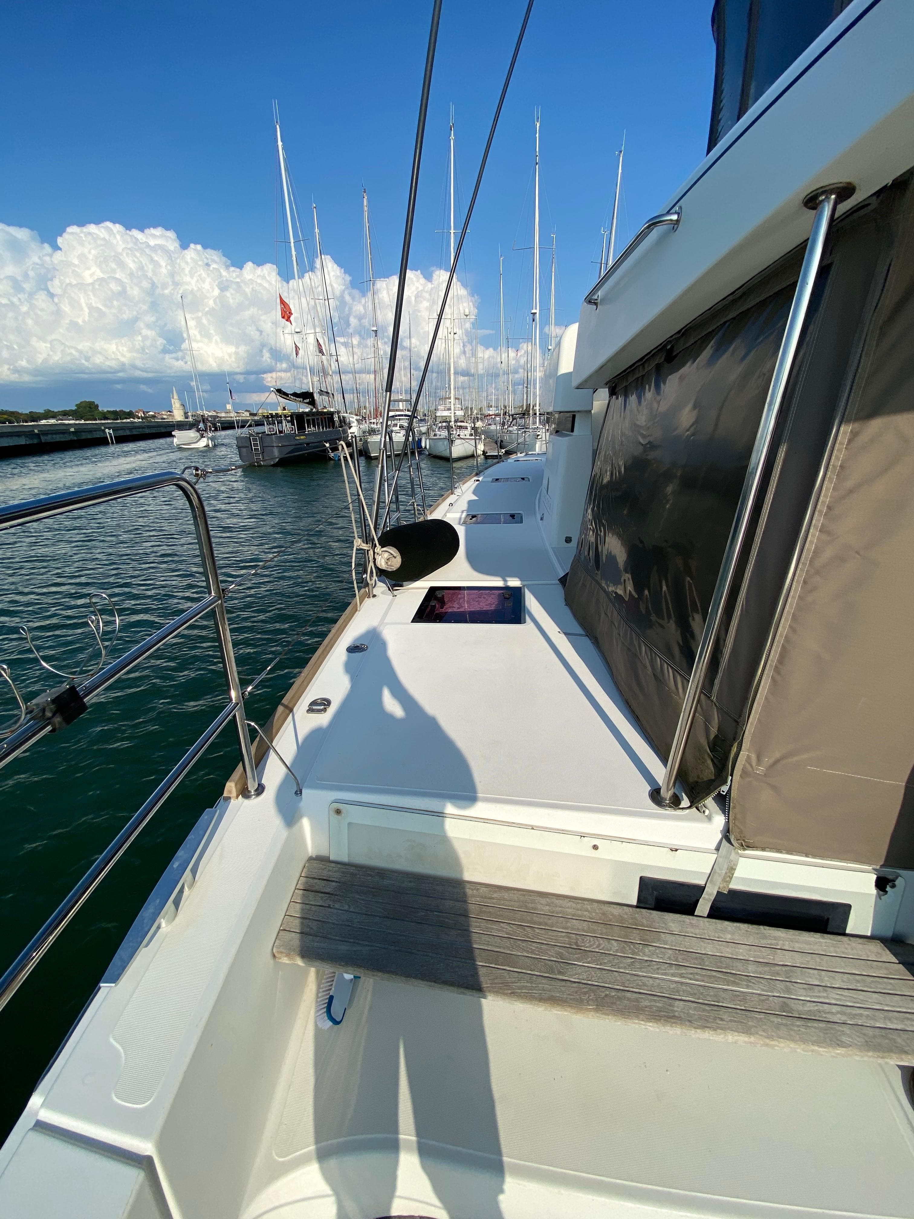Deck view of 2013 Lagoon 52 yacht docked at marina under clear blue sky.