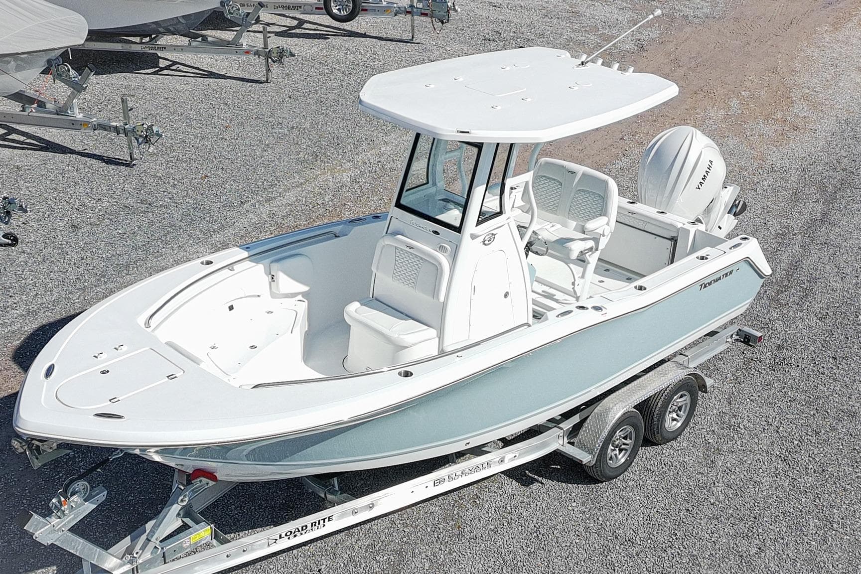 2026 Tidewater 232 CC Adventure boat on trailer, white and blue design, parked on gravel.