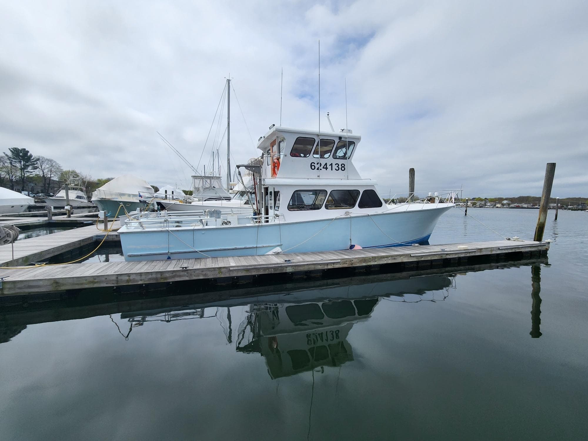 1980 Tuna Rose Brothers boat docked at a marina, reflecting on calm water.