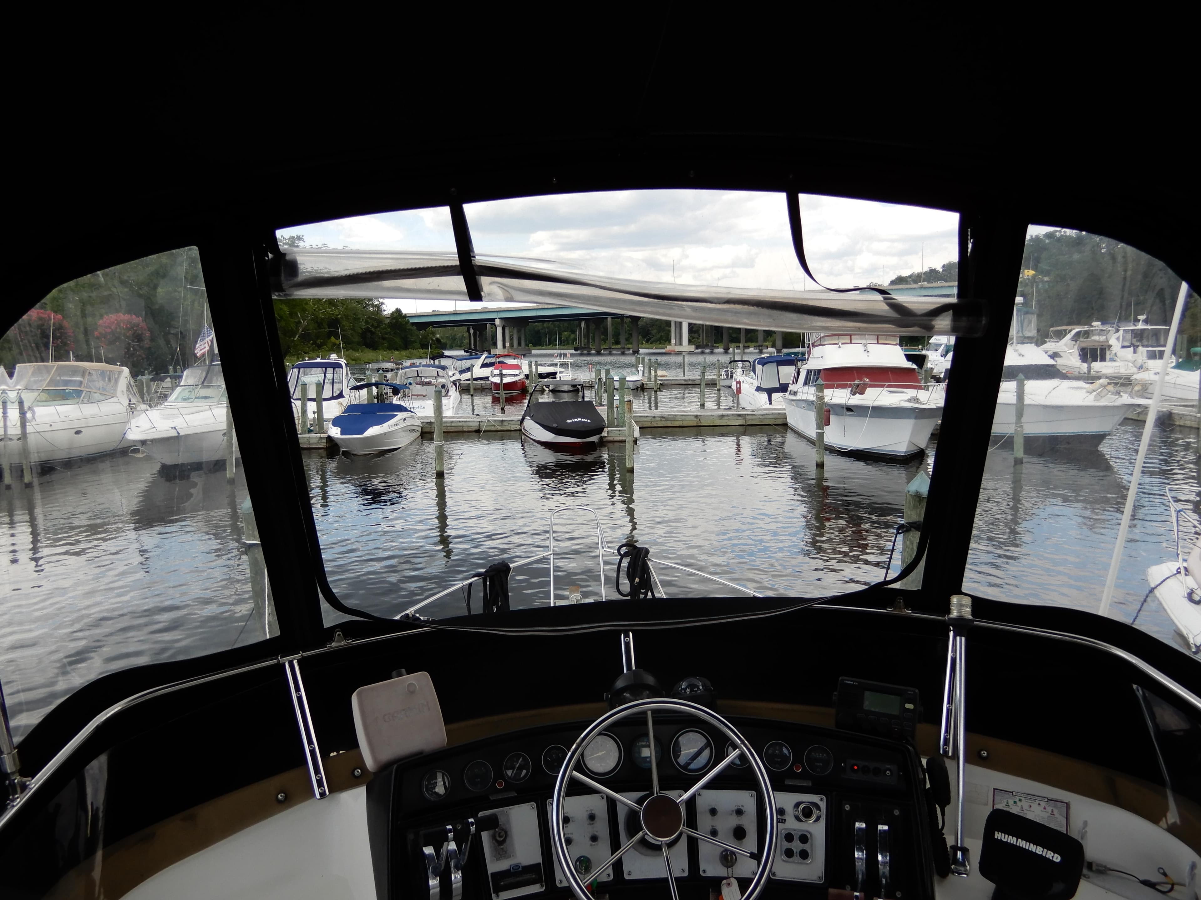 View from 1987 Carver 28 Mariner/Voyager helm, overlooking marina with docked boats.