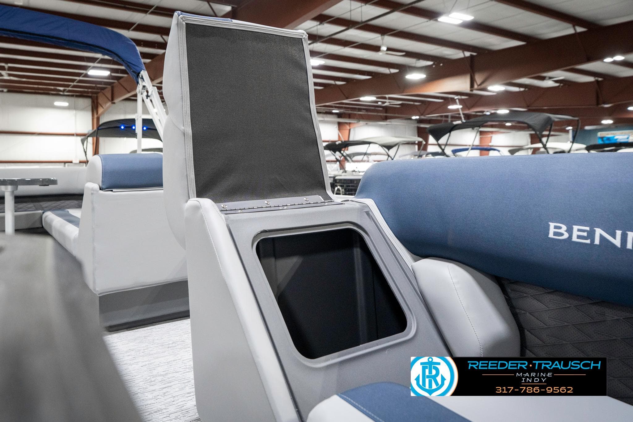 2025 Bennington 22 SLS boat interior with storage compartment open, displayed in a showroom.