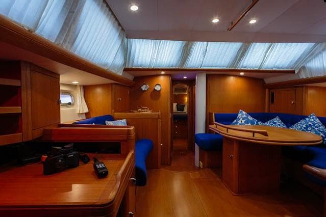 Luxurious interior of a 2004 Oyster 53 yacht with wooden furnishings and blue seating.