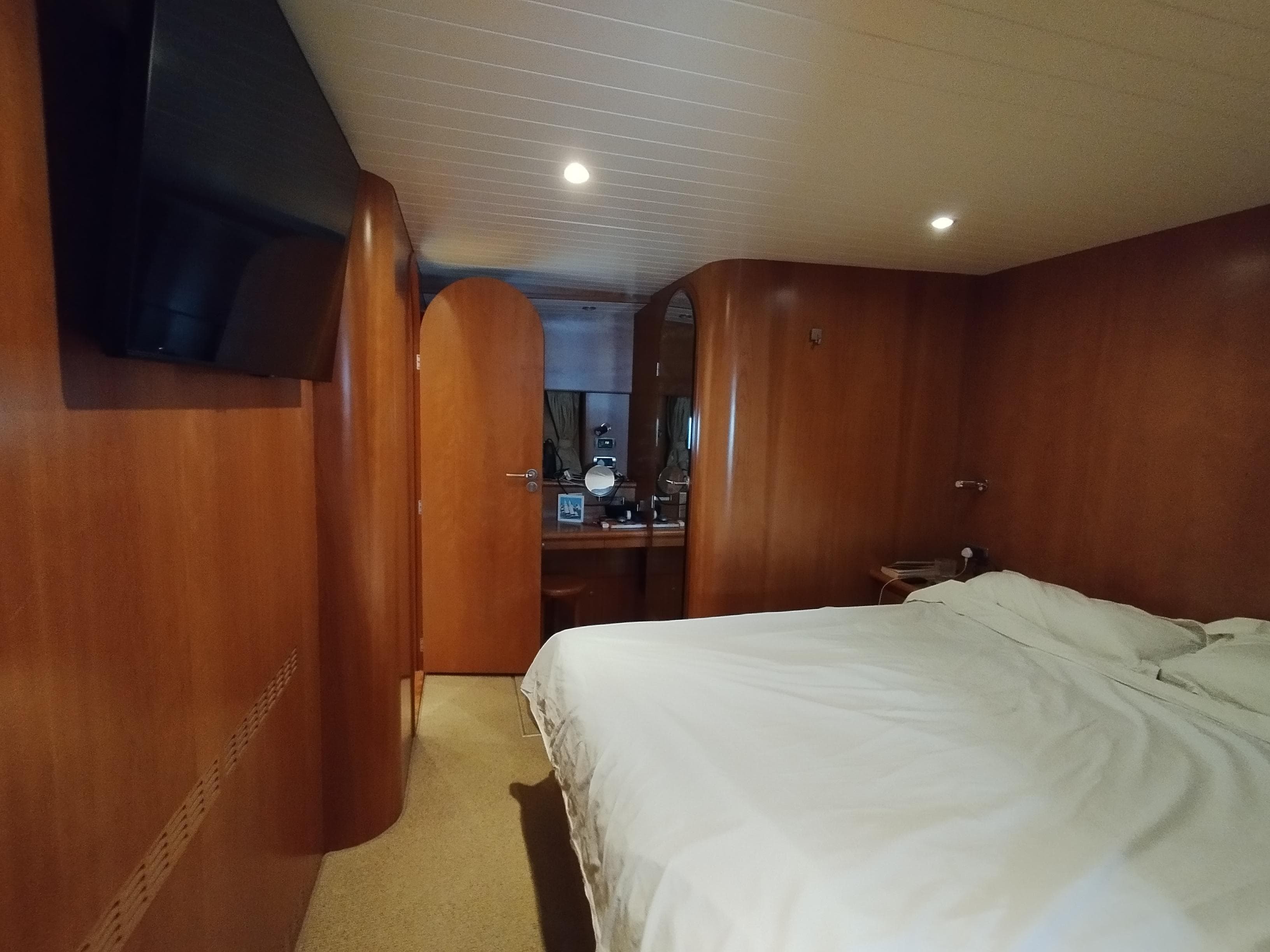 Luxurious cabin interior of Almtrawler Delfino 65 yacht, featuring wood paneling and a cozy bed.