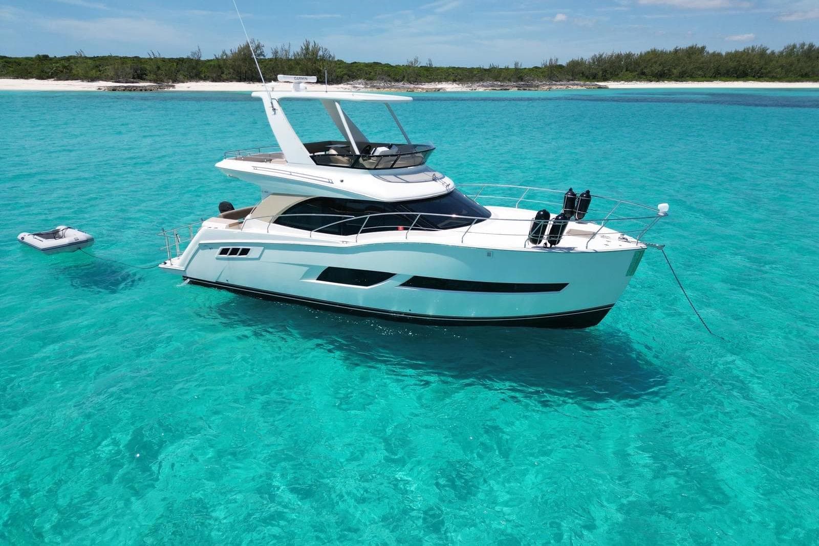 Luxurious 2017 Carver C40 yacht anchored in clear turquoise waters near a sandy beach.