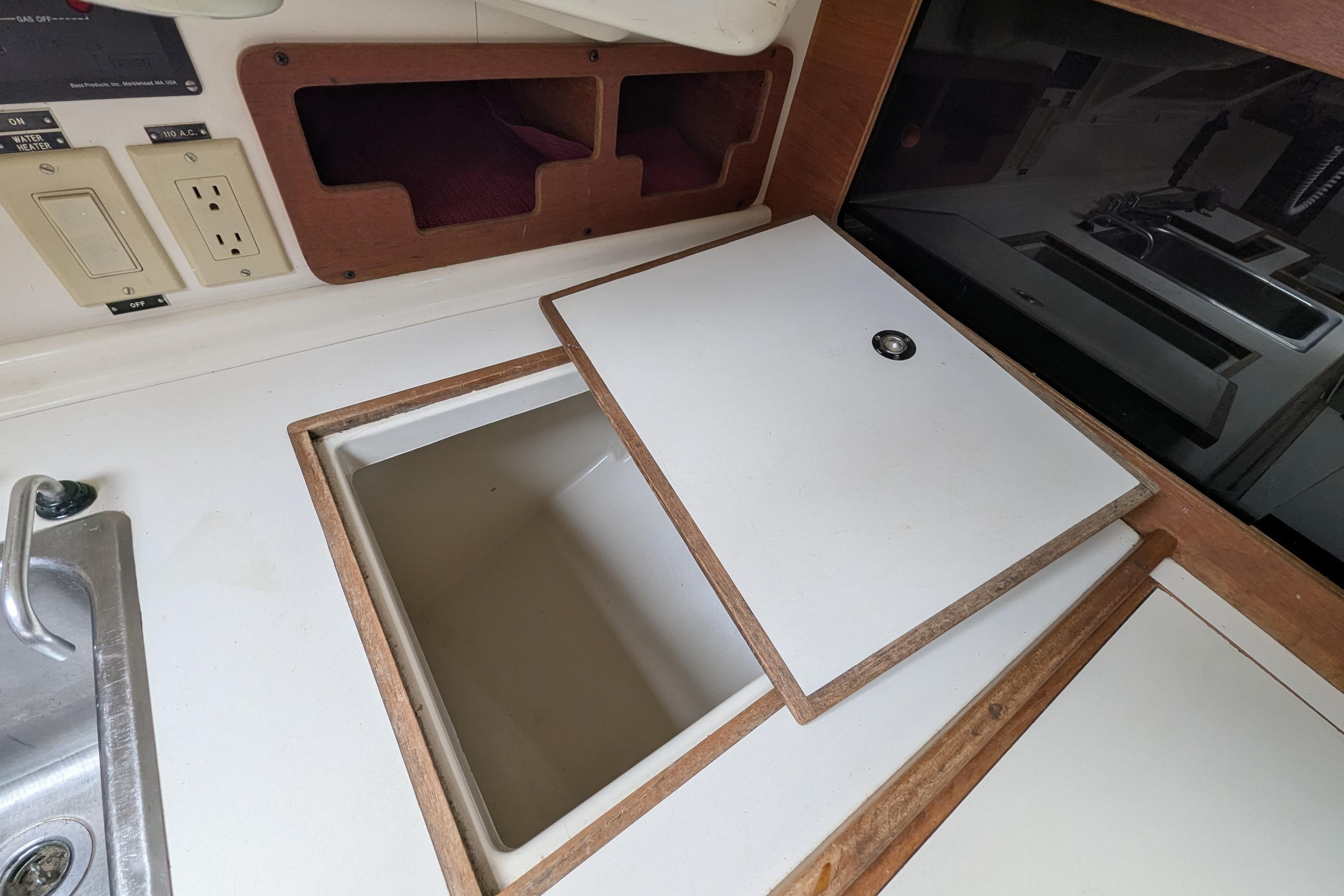 Interior of a 1982 Pearson 323 sailboat showing a storage compartment and sink area.
