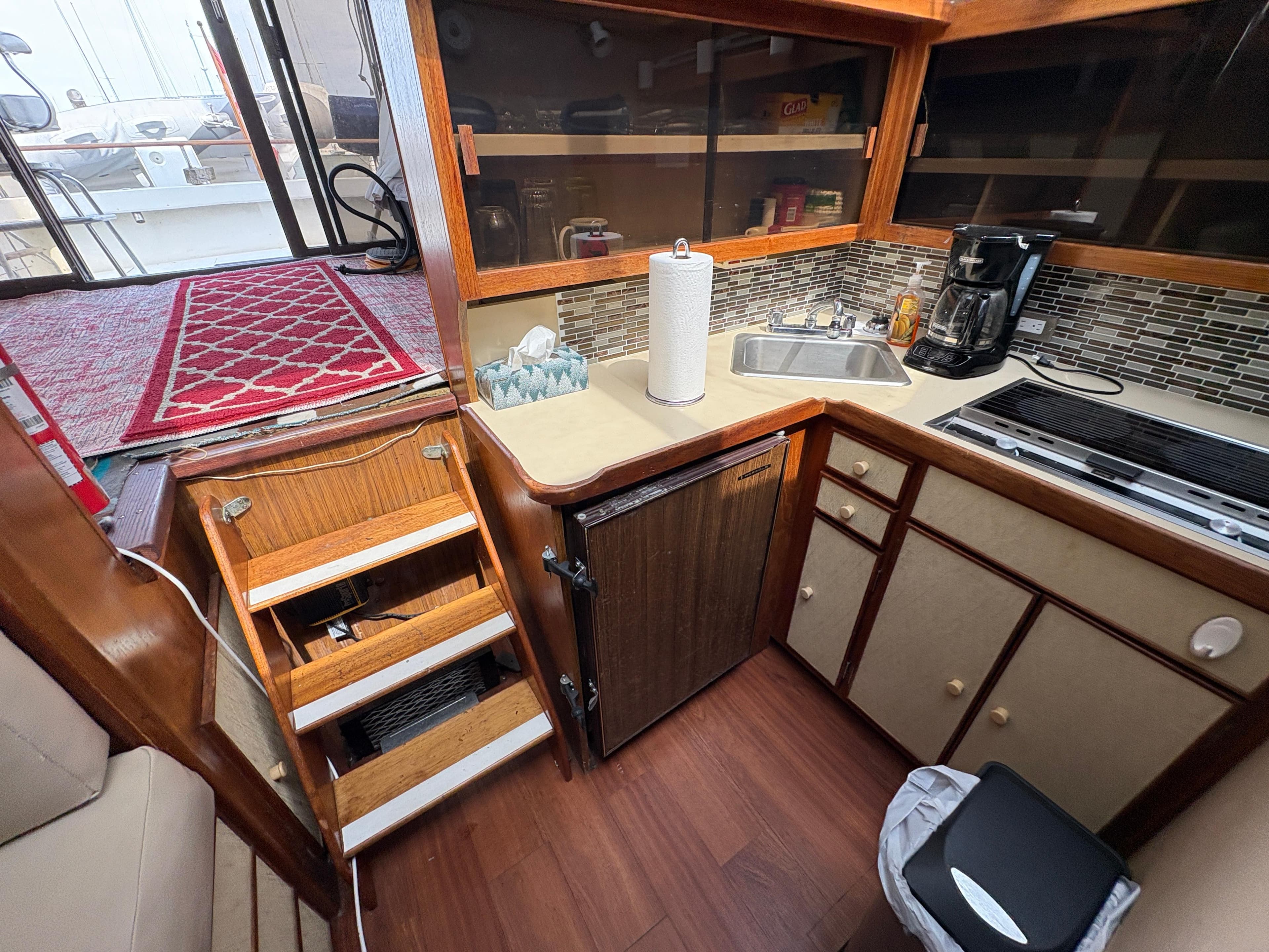 1986 Trojan 32 Sedan boat kitchen with sink, stove, and storage cabinets.