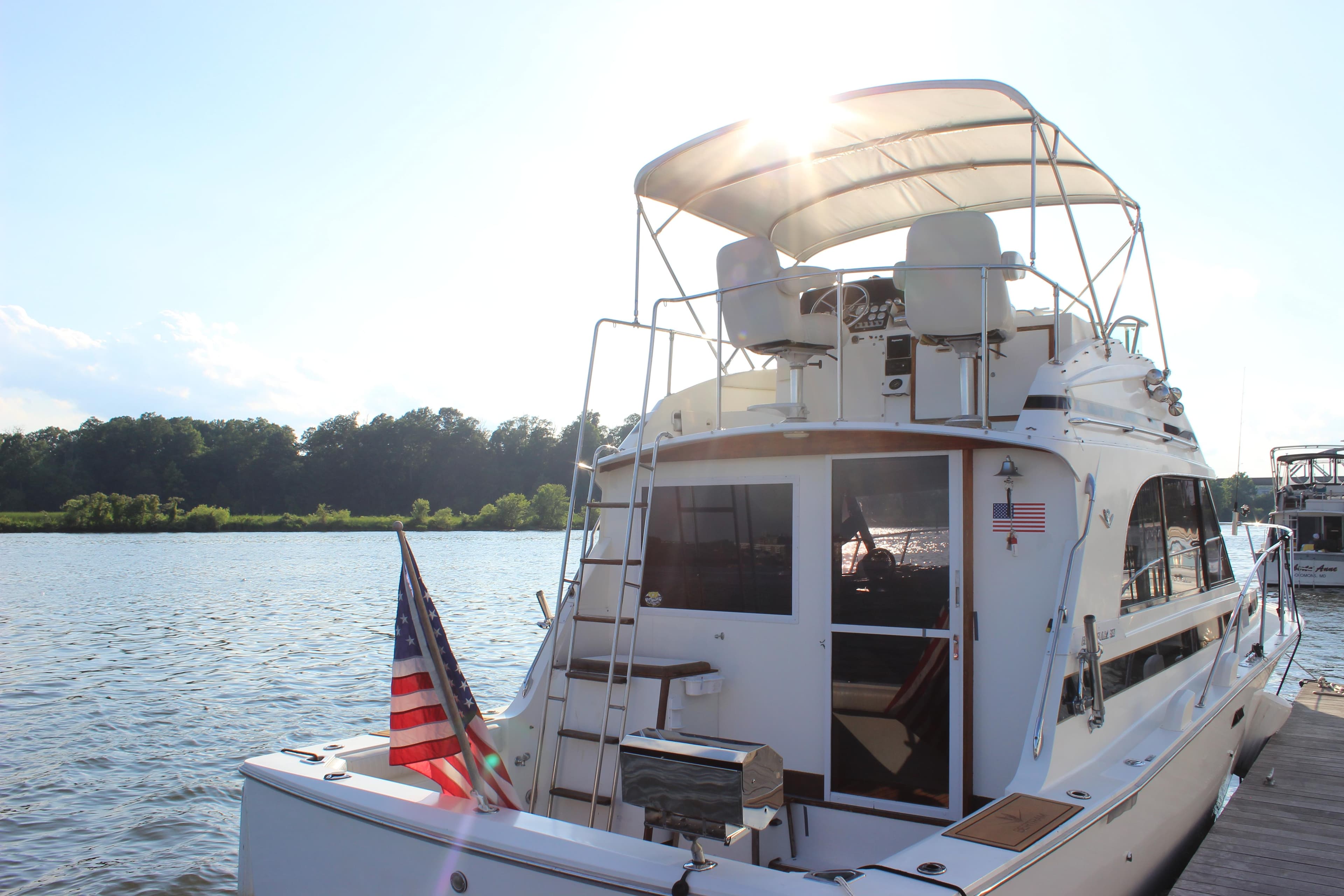 1988 Bertram 33II Flybridge Cruiser docked by a serene river.