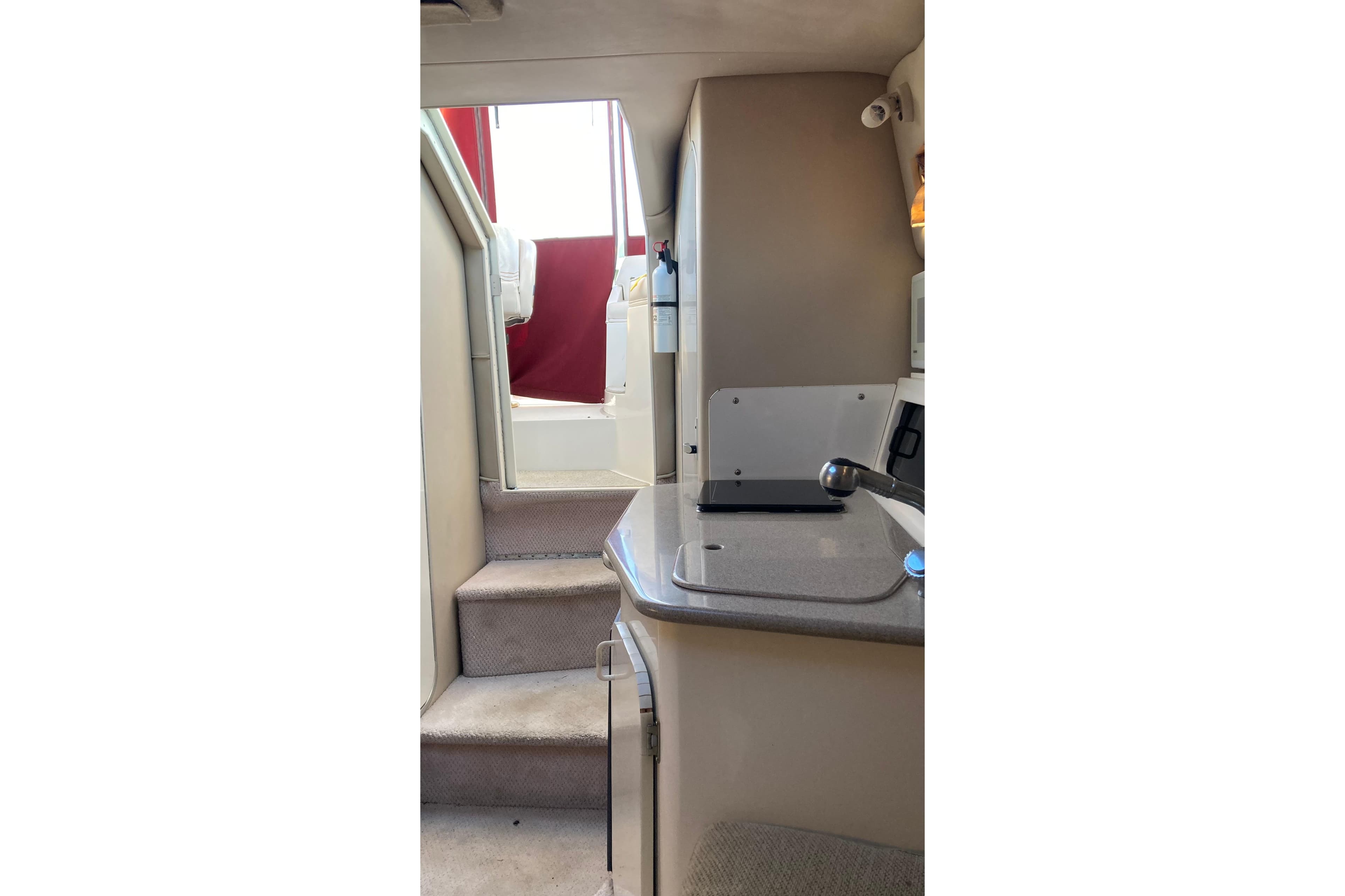 Interior view of 1999 Chaparral Signature 29 boat, featuring stairs and kitchenette.