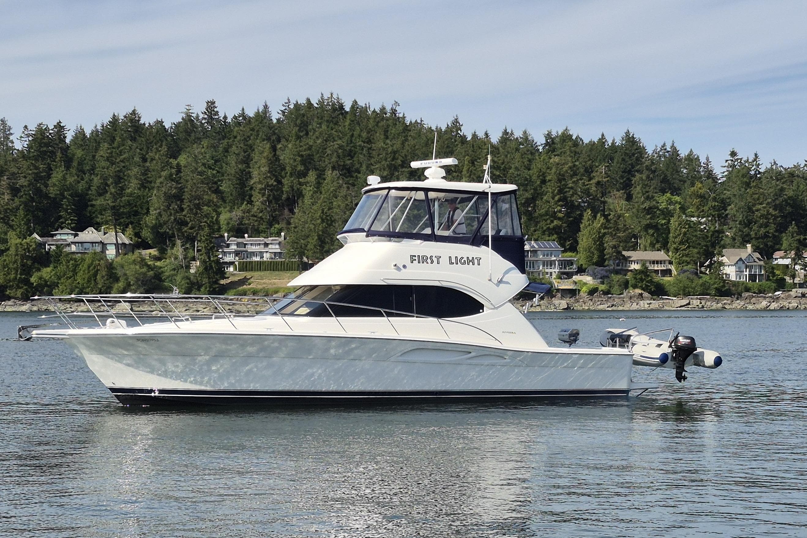 2001 Riviera 40 Flybridge yacht on calm water with forested shoreline background.