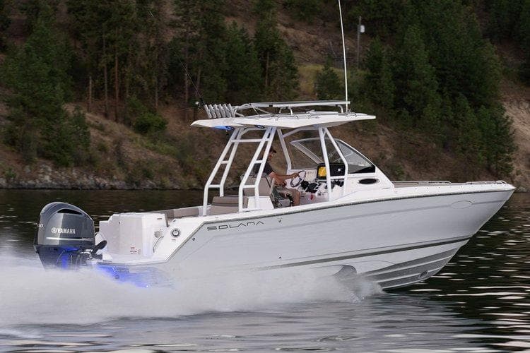 2025 Solara 250 Center Walkaround boat cruising on a lake with forested background.
