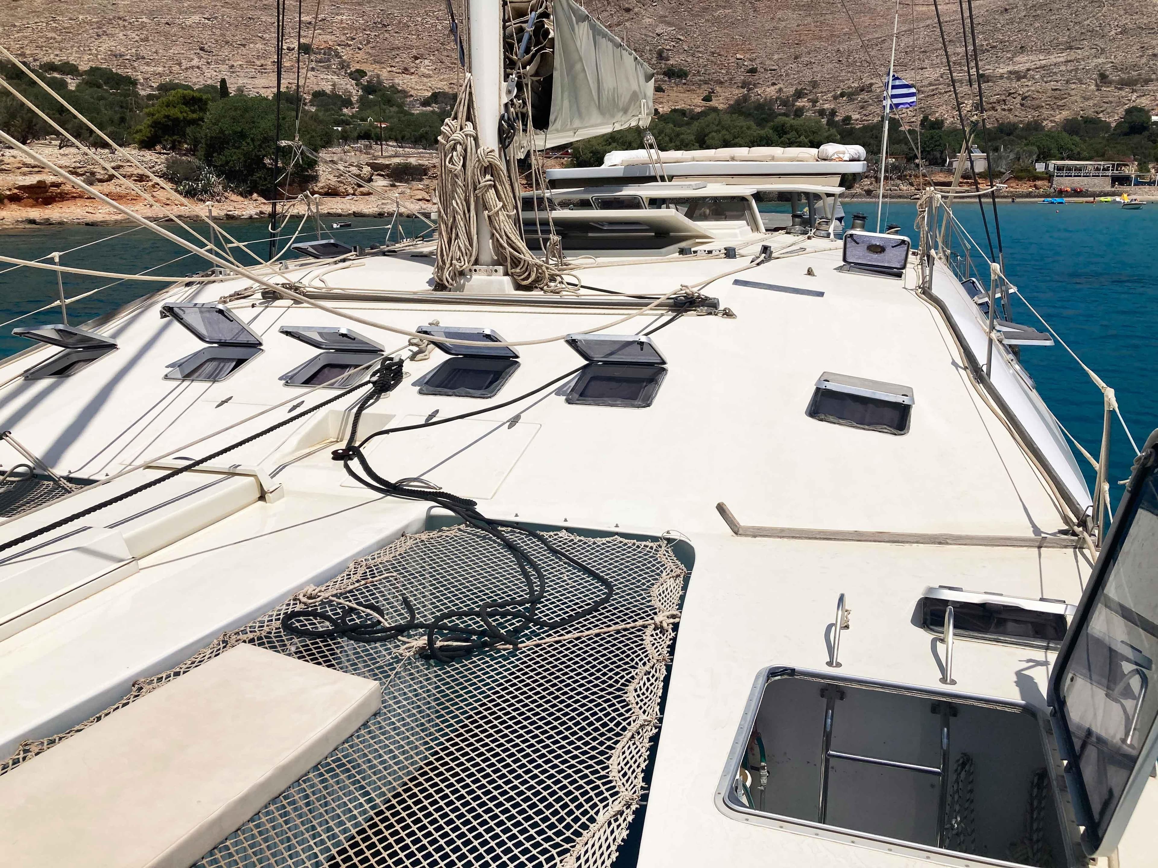 1988 Joubert Custom Trimaran sailboat deck with open hatches and netting, anchored in clear blue waters.