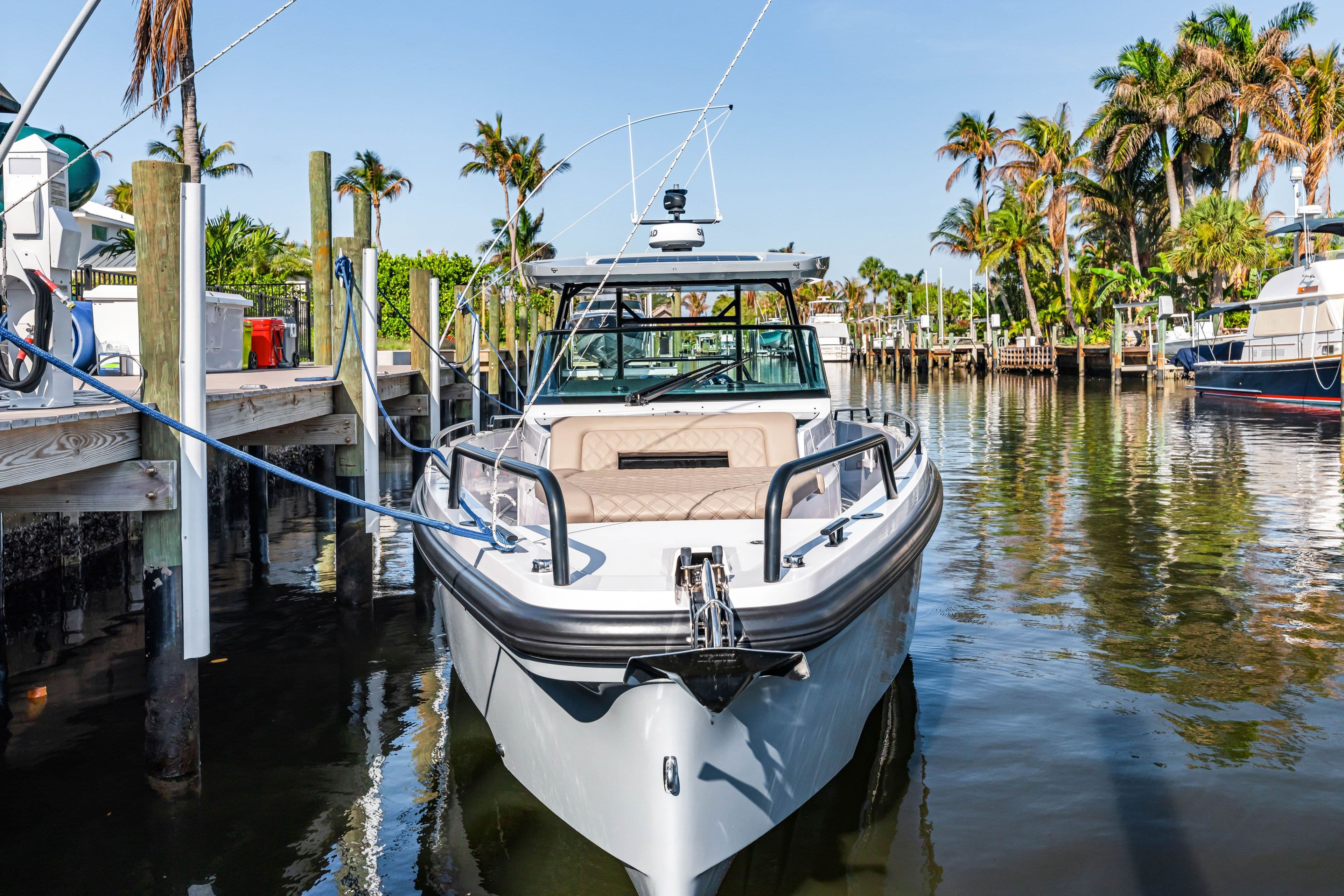 2023 Axopar 37 Sun-Top boat docked, surrounded by palm trees.