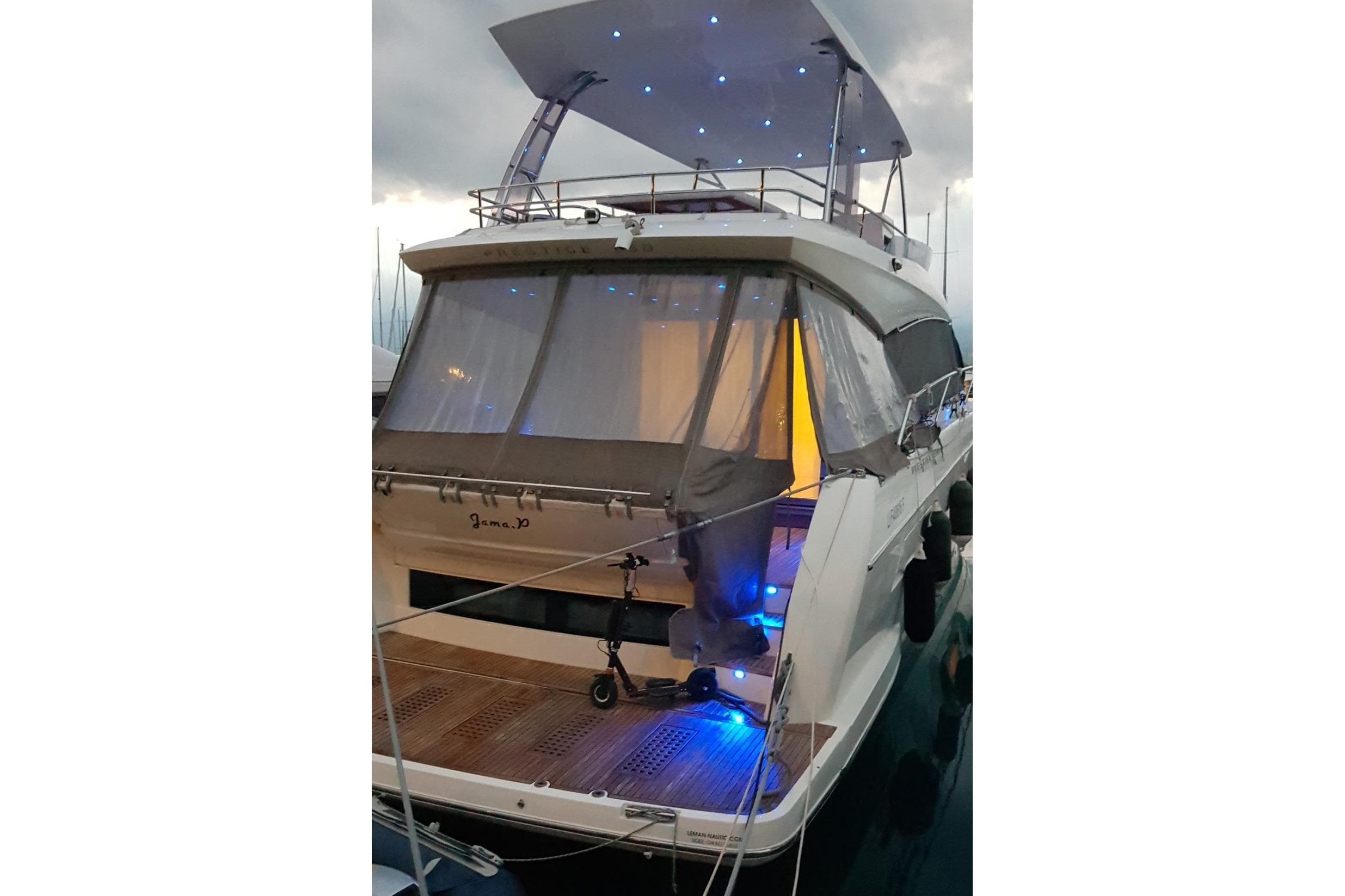 2016 Prestige 550 yacht with illuminated deck and canopy at dusk.