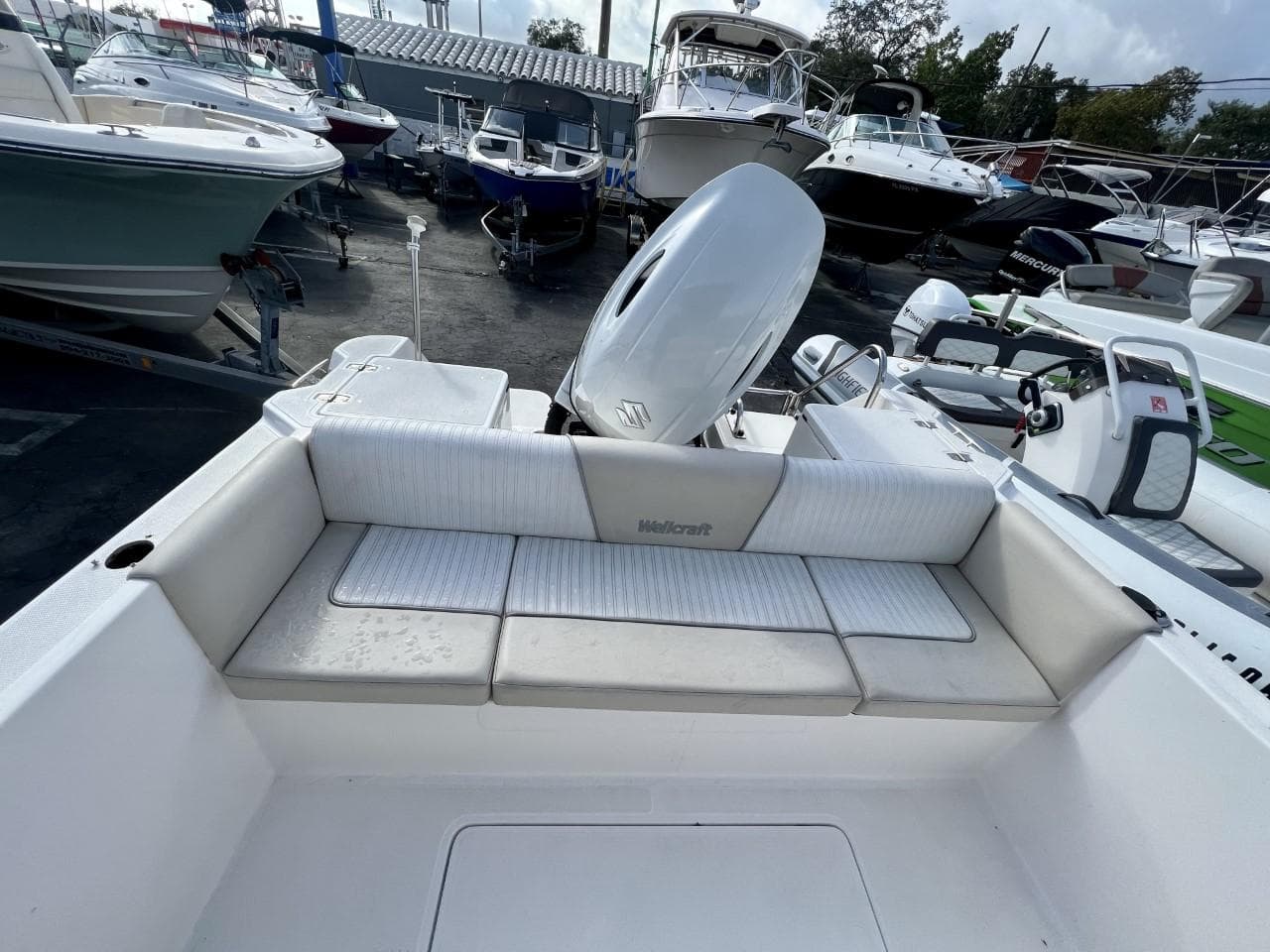 2022 Wellcraft 220CC boat with cushioned seating and outboard motor in a marina.