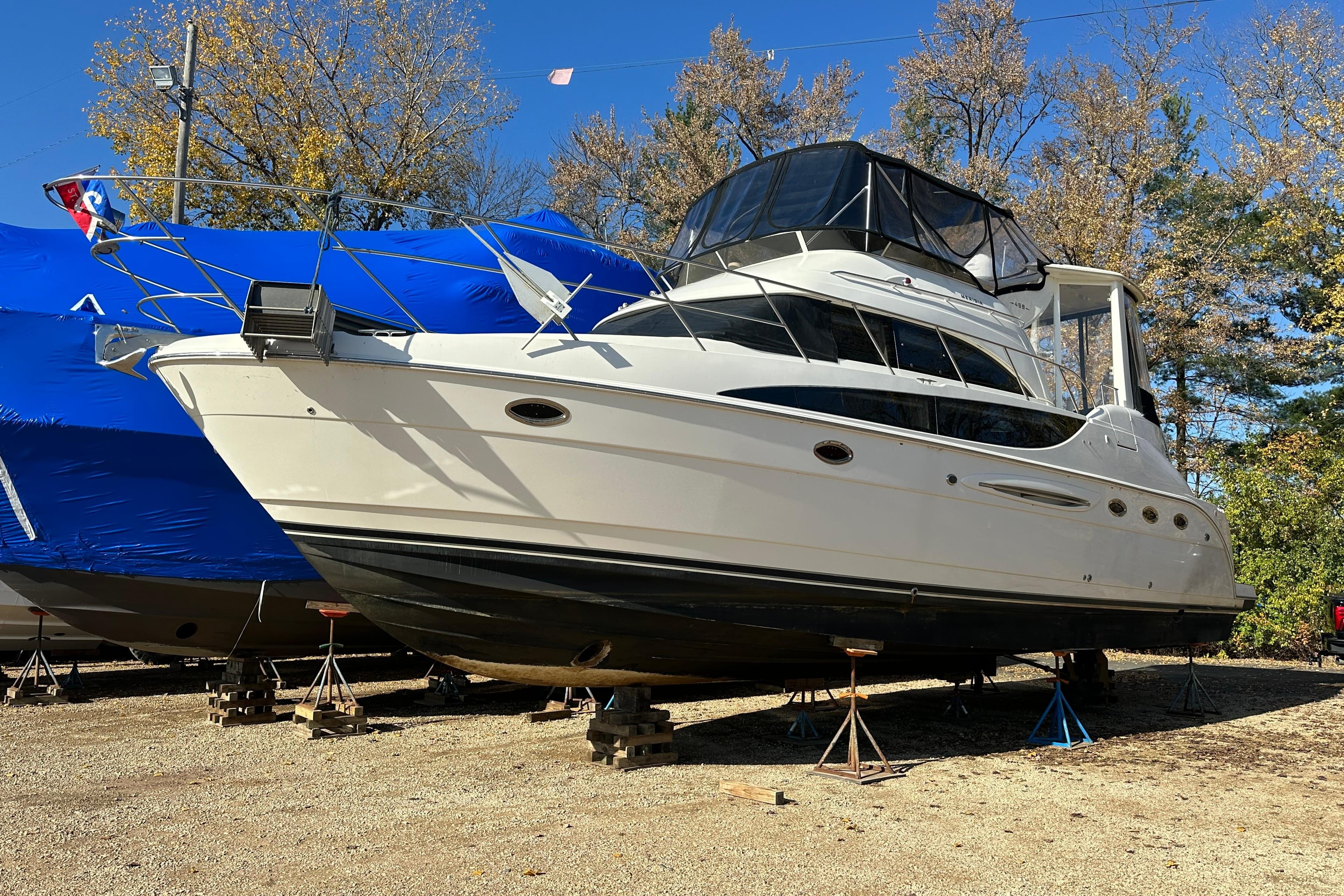 2004 Meridian 459 Motoryacht on stands, surrounded by trees and blue tarps.