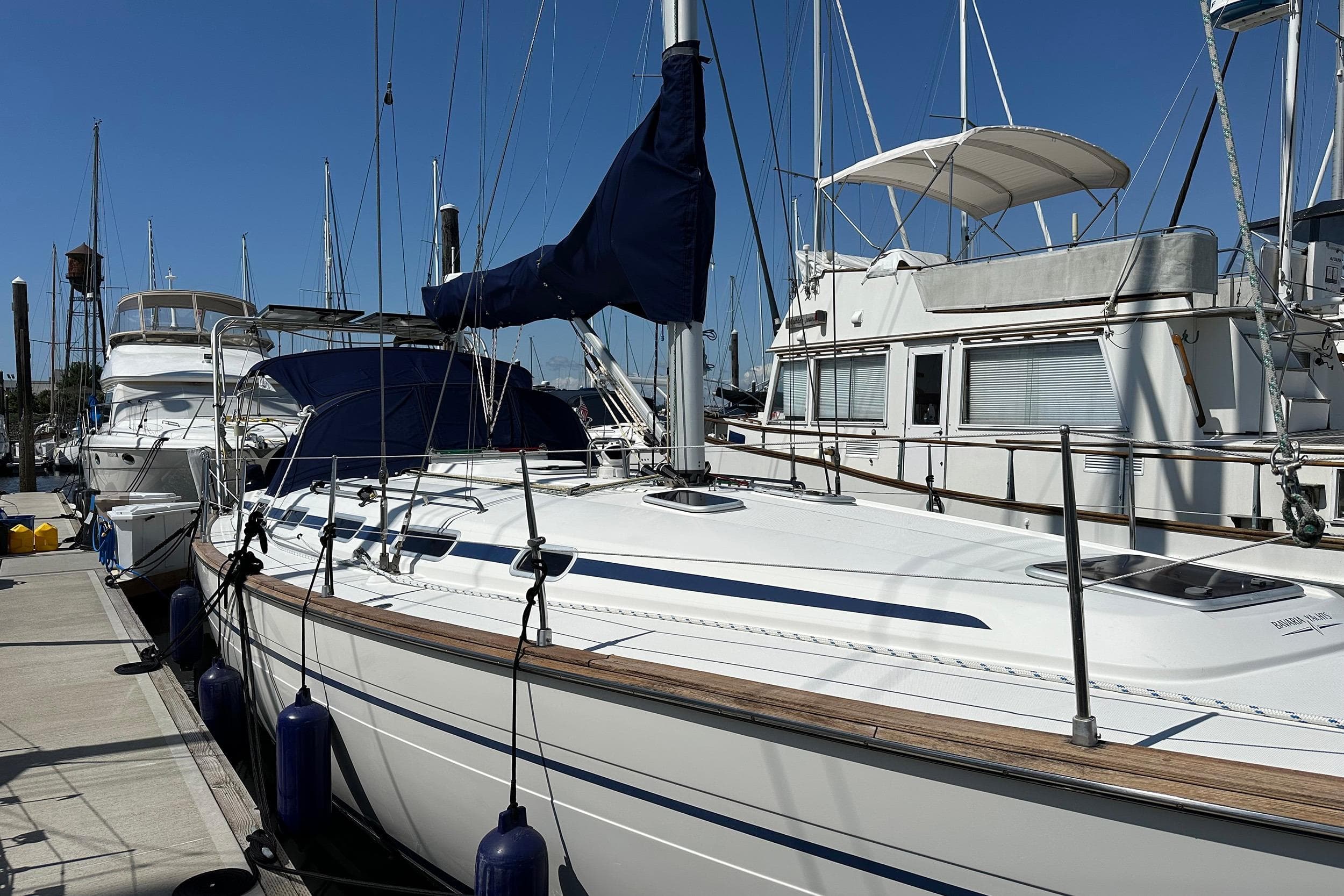 2003 Bavaria 44 sailboat docked at marina under clear blue sky.