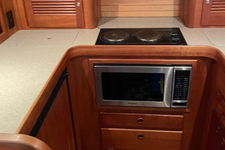 2002 Sabre 36 yacht kitchen with microwave, stovetop, and wooden cabinetry.