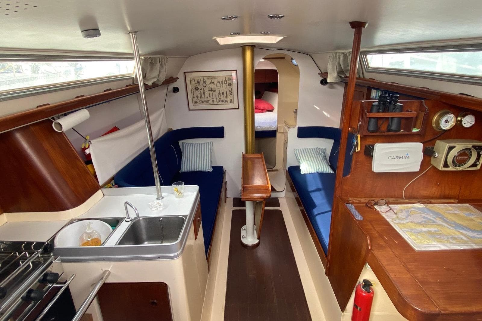 1977 Nicholson 31 yacht interior with kitchen, seating, navigation equipment, and cozy sleeping area.